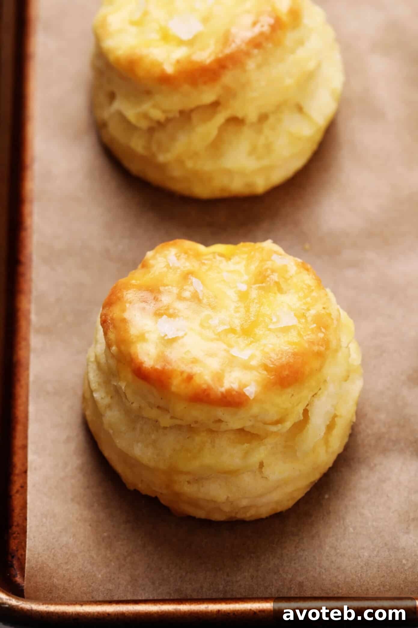 My favorite homemade buttermilk biscuit recipe -- easy to make, perfectly soft and tall and flaky, and always SO buttery and delicious. Serve them for breakfast with jam or gravy, as a side dish for lunch or dinner, or as a topping for chicken pot pie or your favorite casserole! | gimmesomeoven.com #biscuit #roll #bread #recipe #buttermilk #breakfast #brunch #side #vegetarian #baking Closeup of homemade buttermilk biscuits generously sprinkled with flaky sea salt.