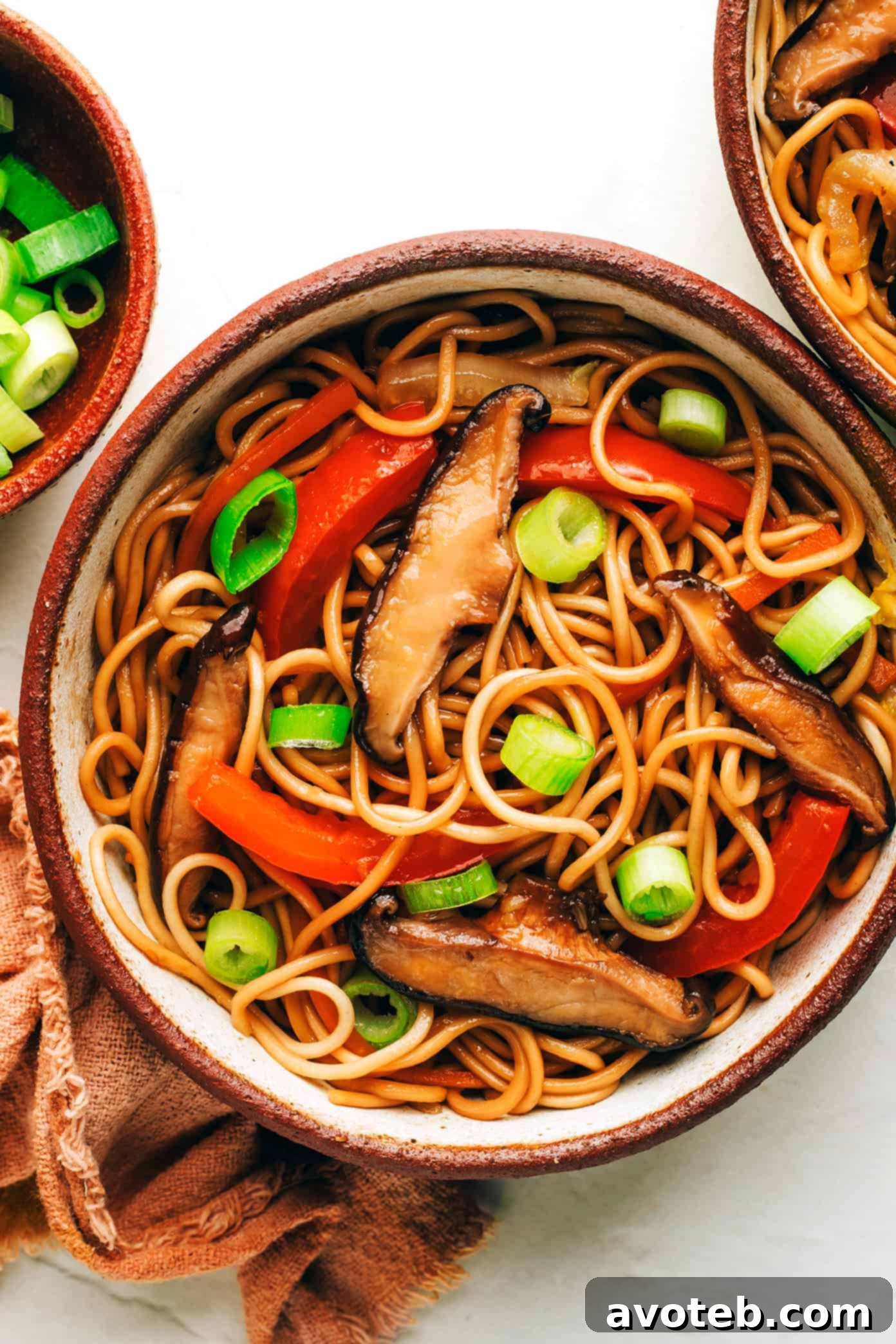 This Chinese-inspired chow mein recipe is easy to whip up in just 25 minutes and tossed with a delicious stir-fry sauce. Feel free to add beef, chicken, pork, shrimp, tofu, or any other extra veggies you might like too! | gimmesomeoven.com Bowl of chow mein with mushrooms, red peppers and green onions