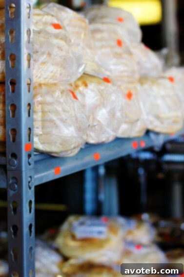 Freshly baked, warm pita bread stacked at a vendor stall, inviting market-goers to sample its deliciousness.