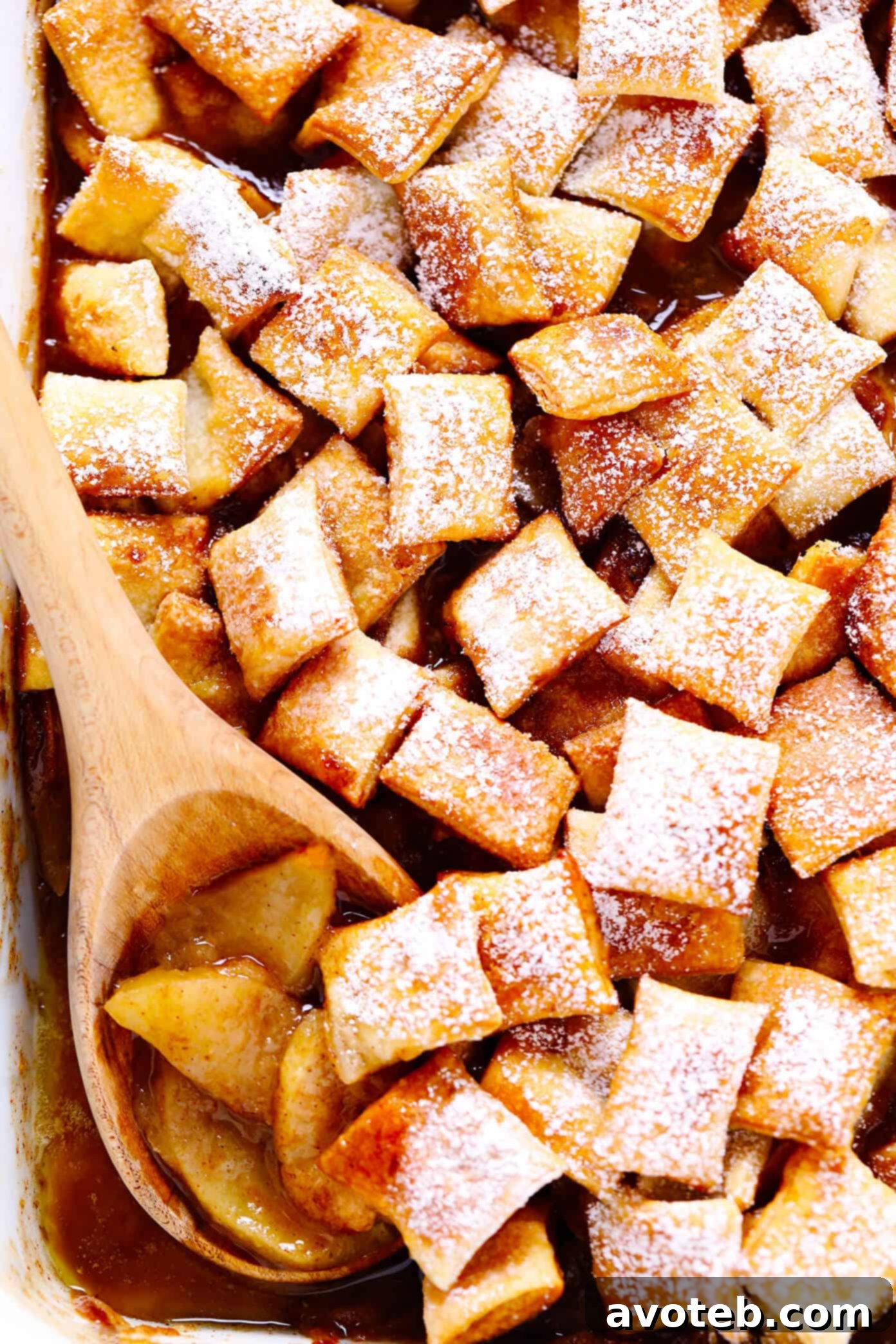 This easy Apple Pandowdy recipe is made with a delicious baked apple cinnamon pie filling topped with toasted puff pastry bites and a light dusting of powdered sugar. Absolutely delicious served warm with vanilla ice cream, and the perfect dessert for the holidays. | gimmesomeoven.com #apple #pandowdy #pie #dessert #bake #crisp #puffpastry #filling #thanksathing #christmas Apple Pandowdy in Pan with Wooden Spoon