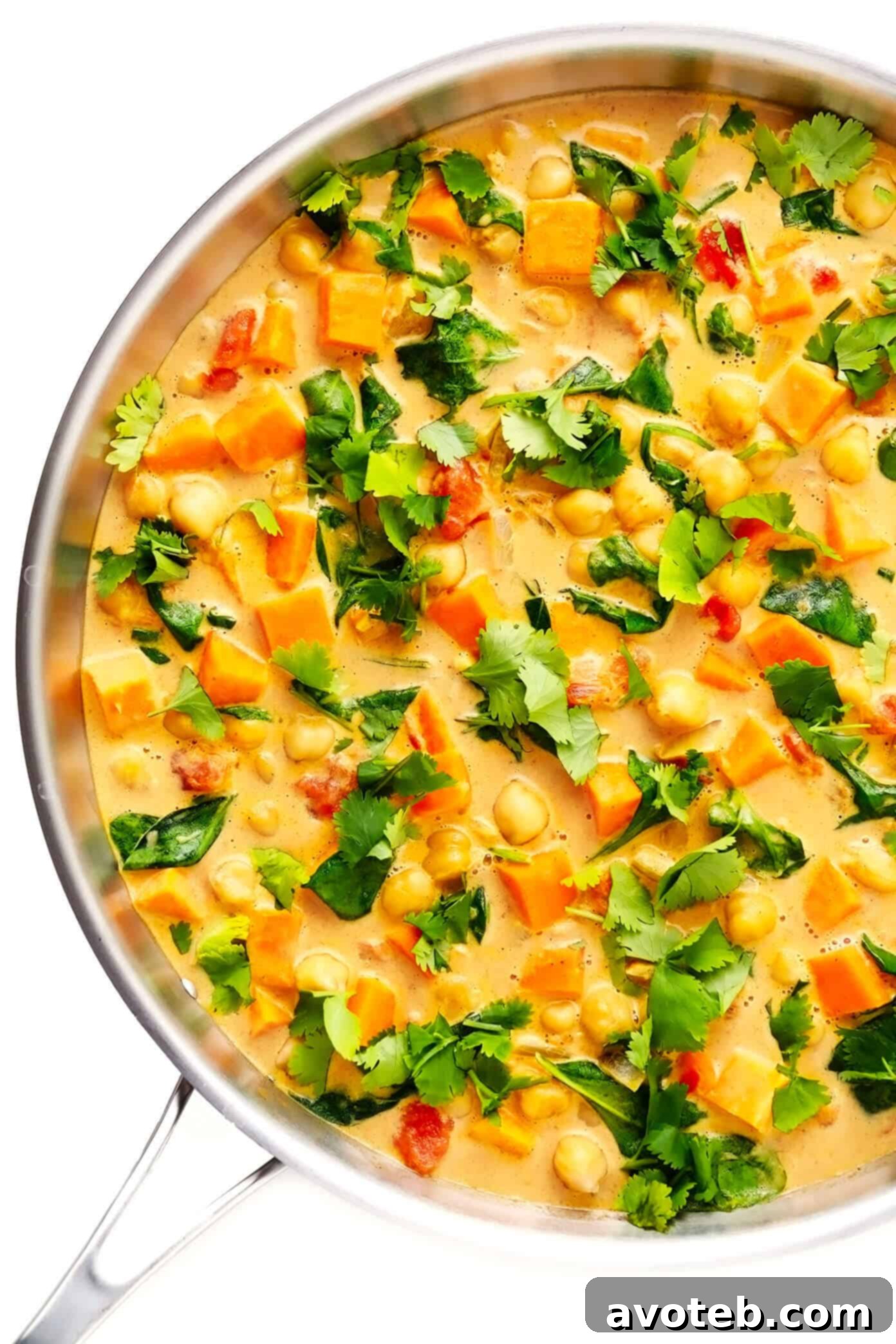 A large sauté pan filled with creamy Sweet Potato Chickpea Coconut Curry, garnished with fresh cilantro, ready to be dished out and enjoyed.