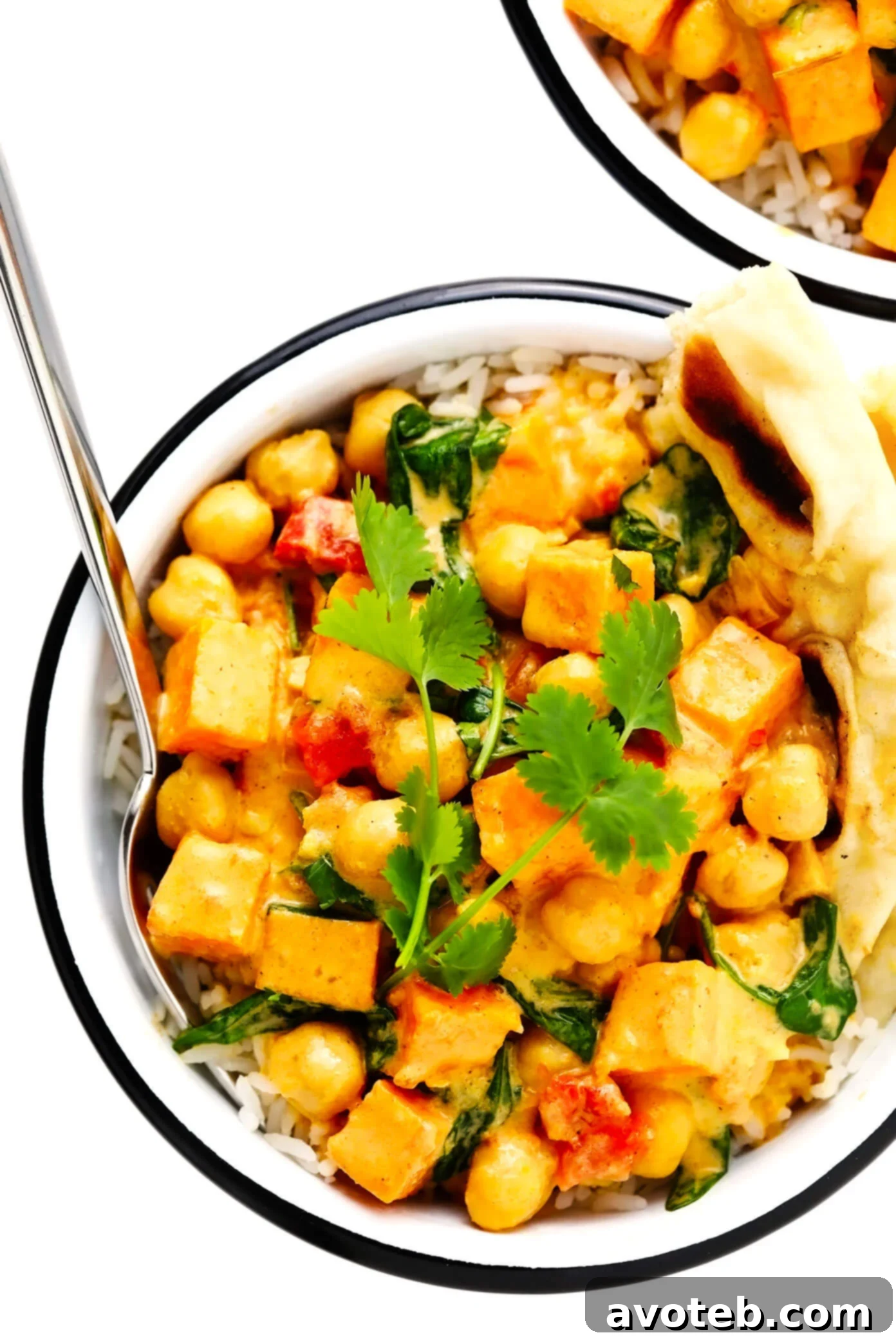 A vibrant bowl of Sweet Potato Chickpea Coconut Curry, served alongside fragrant rice and soft naan bread, creating a complete and satisfying meal.
