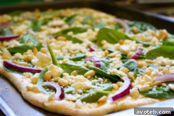 Ingredients for Spinach Feta and Pine Nut Pizza laid out for preparation, including fresh spinach, feta, and pine nuts
