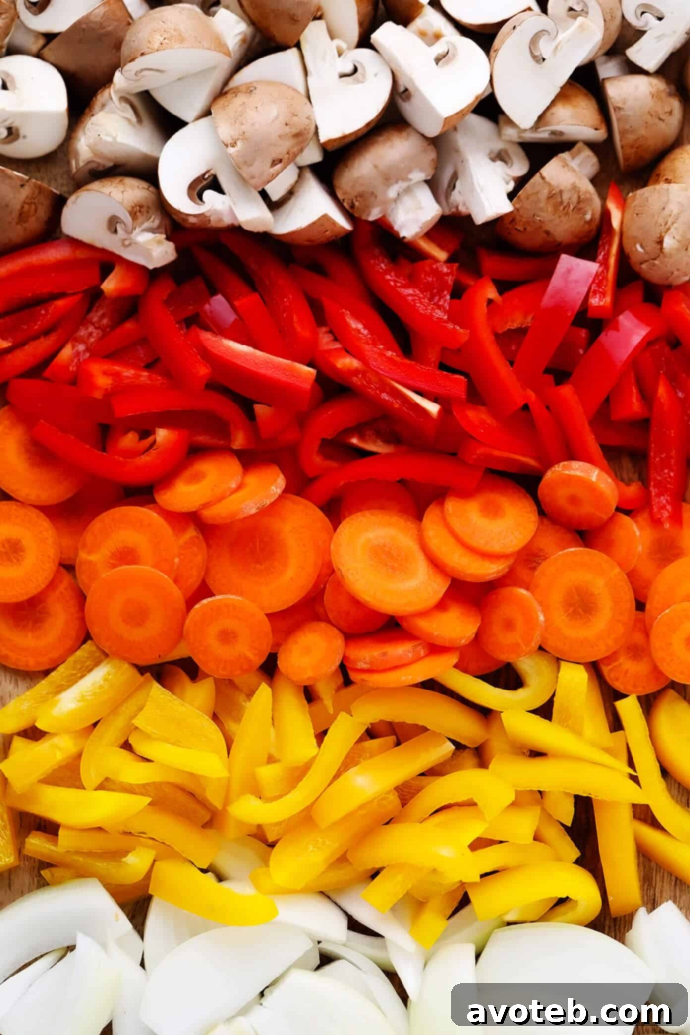 A colorful array of freshly chopped vegetables including bell peppers, carrots, onions, and mushrooms, prepped for Thai Chicken Curry.