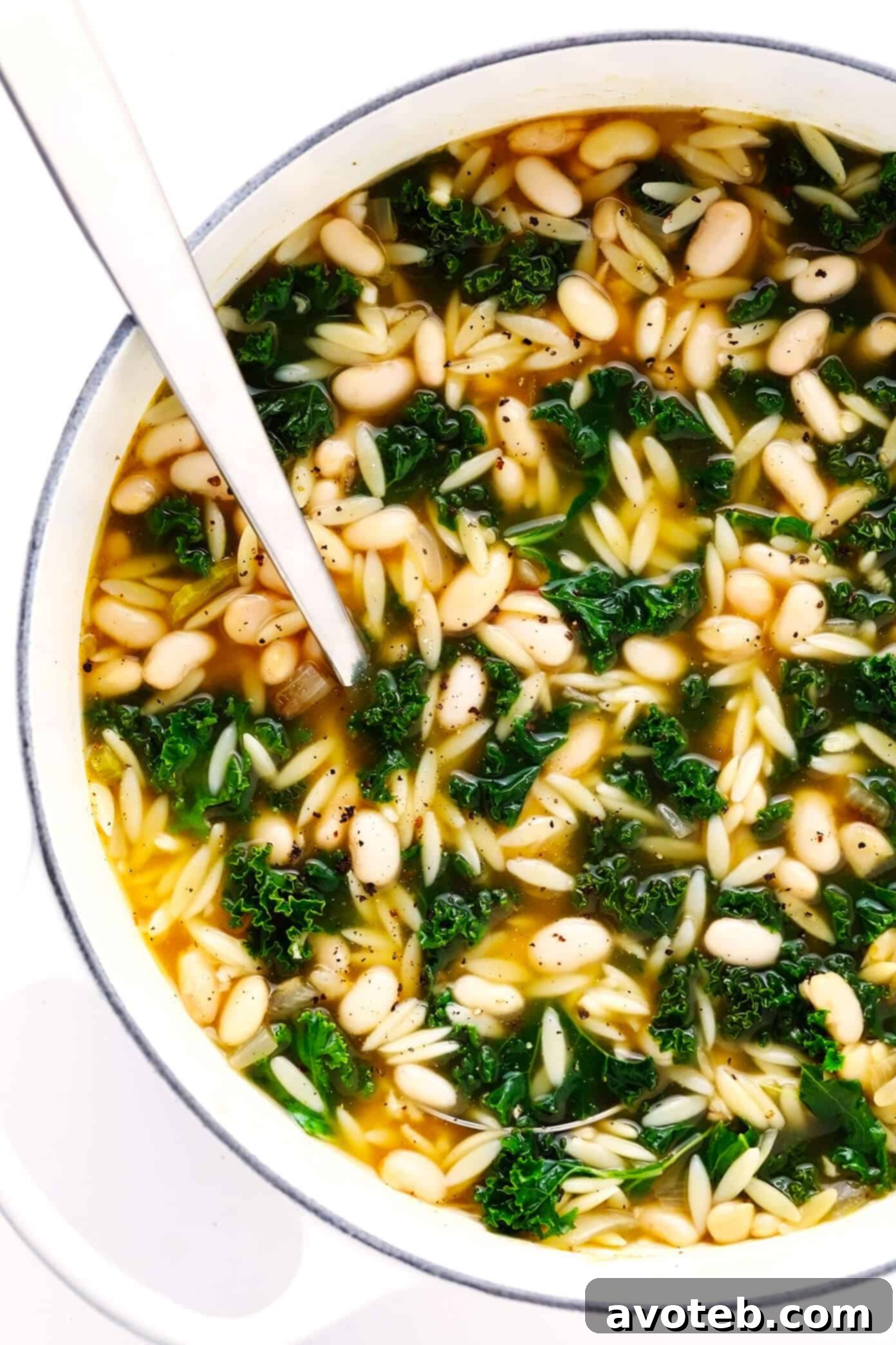 This simple Kale, White Bean and Orzo Soup is made with a cozy lemony-rosemary broth, topped with Parmesan cheese, and ready to go in just 30 minutes! A great vegetarian dinner recipe, or feel free to add a protein (chicken, bacon or sausage) if you'd like! | gimmesomeoven.com #soup #orzo #kale #bean #vegetarian #vegan #dinner #healthy Kale, White Bean and Orzo Soup simmering in a stockpot