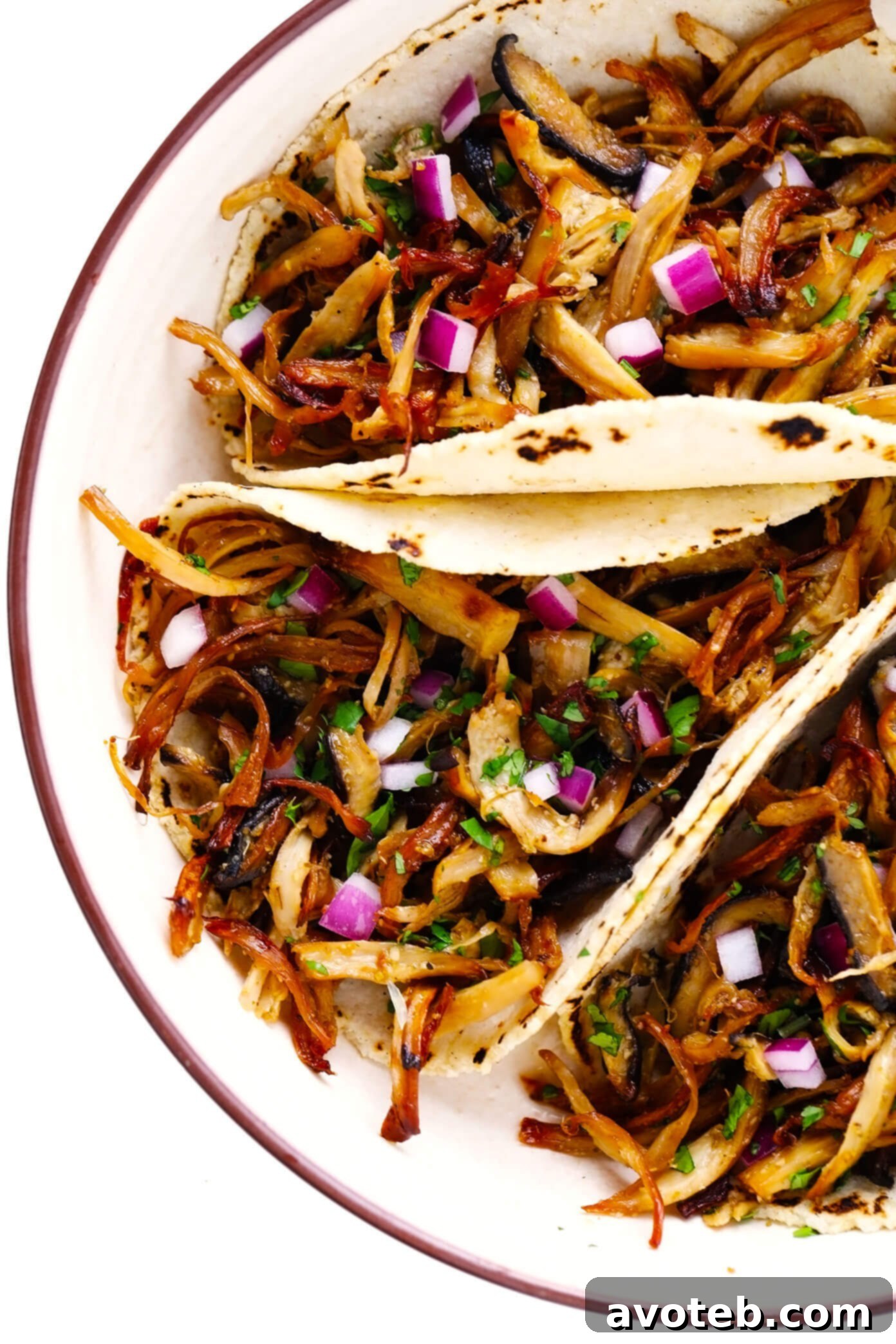 Plate of Mushroom Carnitas Tacos garnished with red onion and cilantro