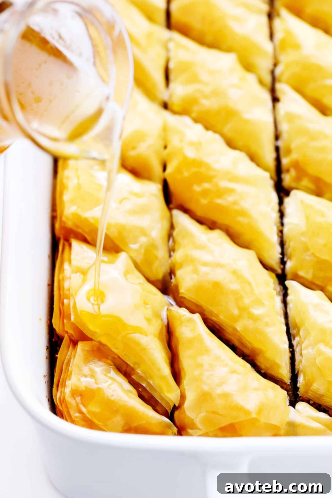 Drizzling chilled honey syrup over hot, freshly baked baklava, creating a delightful sizzle and ensuring crispy layers and optimal syrup absorption.