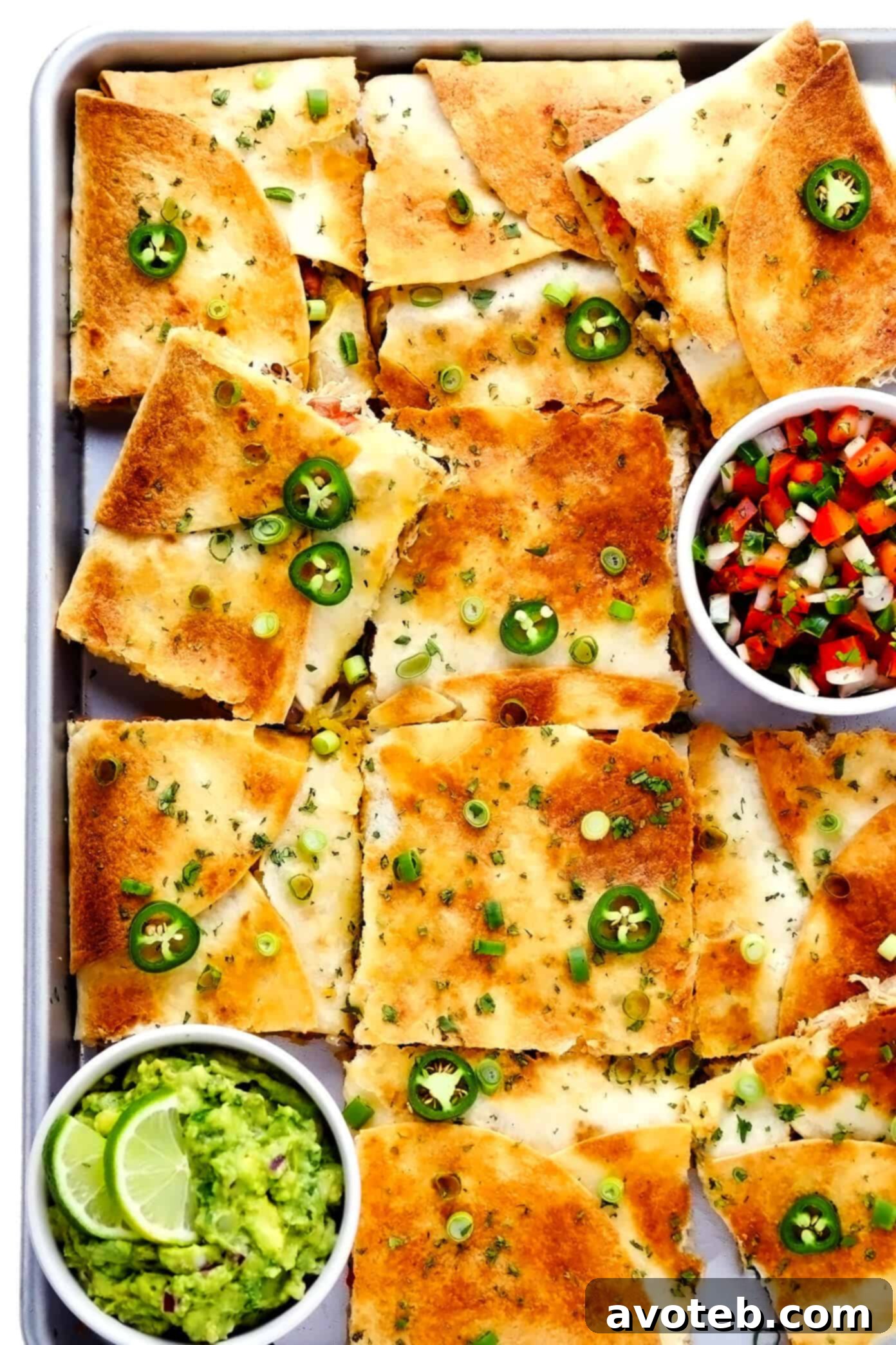 This party-sized chicken sheet pan quesadilla recipe is filled with a zesty mix of cheese, beans, veggies and baked up in a large sheet pan to feed a crowd. Serve as an appetizer, dinner entrée or game day snack with guacamole, salsa, sour cream or any of your favorite dips and enjoy! | gimmesomeoven.com #chicken #quesadilla #mexican #gameday #dinner #party #appetizer #cheese Delicious Chicken Sheet Pan Quesadilla served with fresh guacamole and pico de gallo, ready to be enjoyed by a crowd.
