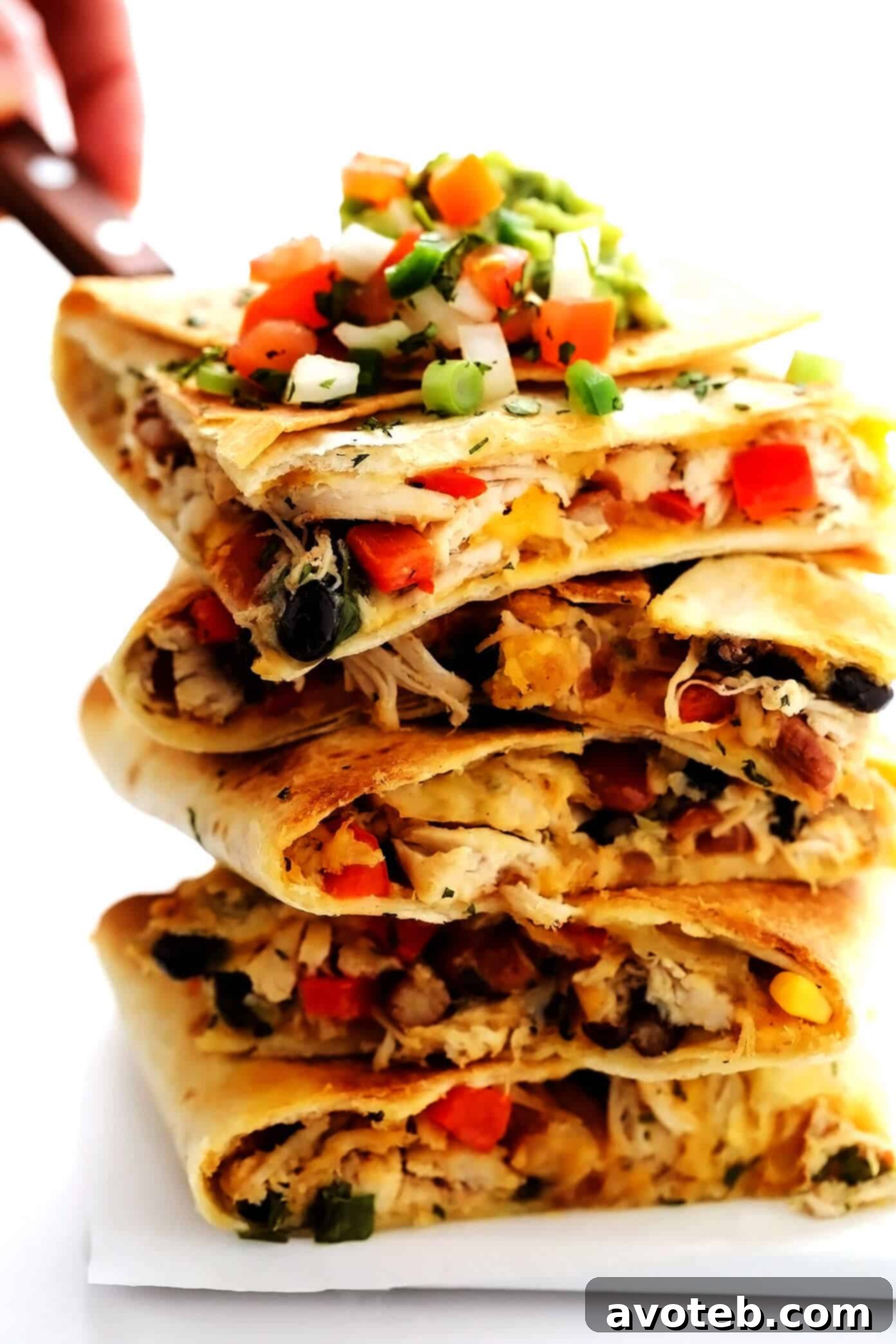 This party-sized chicken sheet pan quesadilla recipe is filled with a zesty mix of cheese, beans, veggies and baked up in a large sheet pan to feed a crowd. Serve as an appetizer, dinner entrée or game day snack with guacamole, salsa, sour cream or any of your favorite dips and enjoy! | gimmesomeoven.com #chicken #quesadilla #mexican #gameday #dinner #party #appetizer #cheese Close-up shot of layered Chicken Sheet Pan Quesadilla slices, highlighting the generous filling and melted cheese.