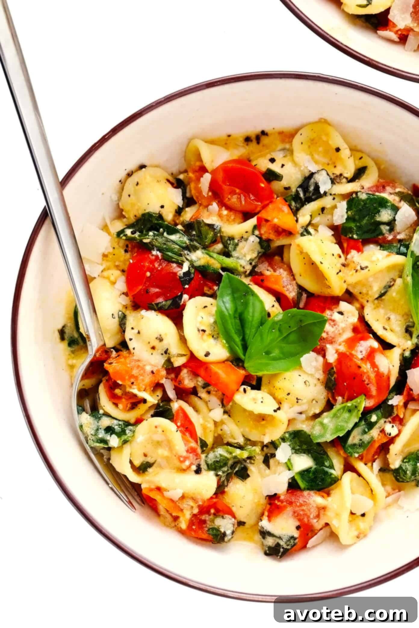 My spin on TikTok's famous baked feta pasta recipe is super-easy to make in the oven, featuring creamy melted feta cheese, burst cherry tomatoes, fresh spinach, and the yummiest garlic white wine basil sauce. Feel free to add a protein (chicken, shrimp, salmon, etc) or extra veggies too, and you're welcome to use gluten-free pasta to make this recipe gf. | gimmesomeoven.com #pasta #feta #cheese #vegetarian #dinner #easy #uunifetapasta #tomato #sauce TikTok Baked Feta Pasta served in individual bowls, garnished with Parmesan.