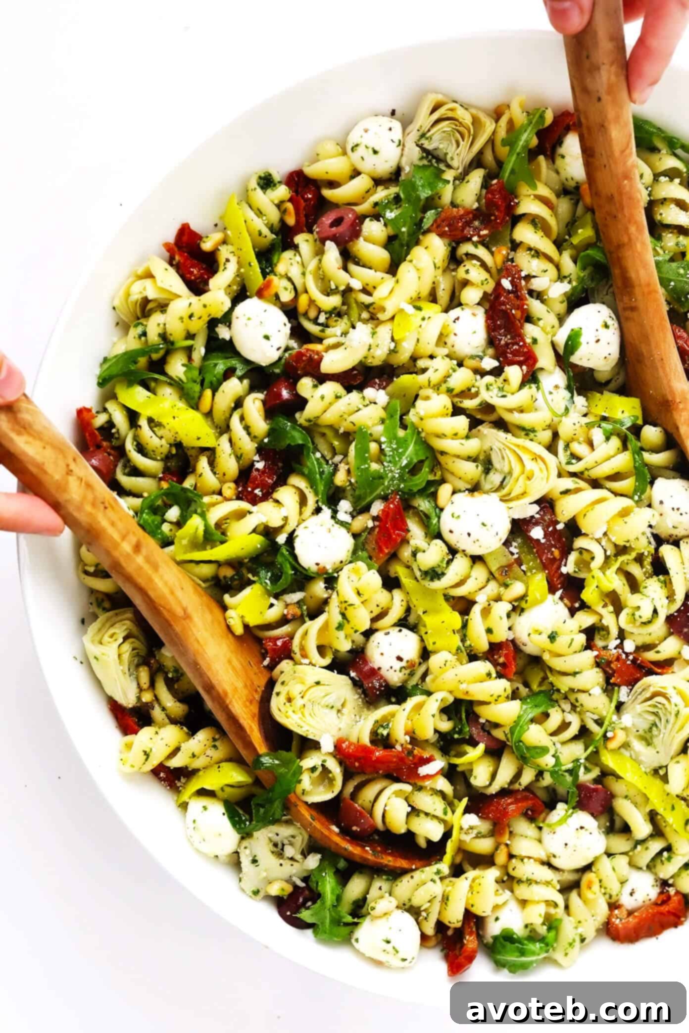 Italian Pesto Pasta Salad in a large bowl with tongs
