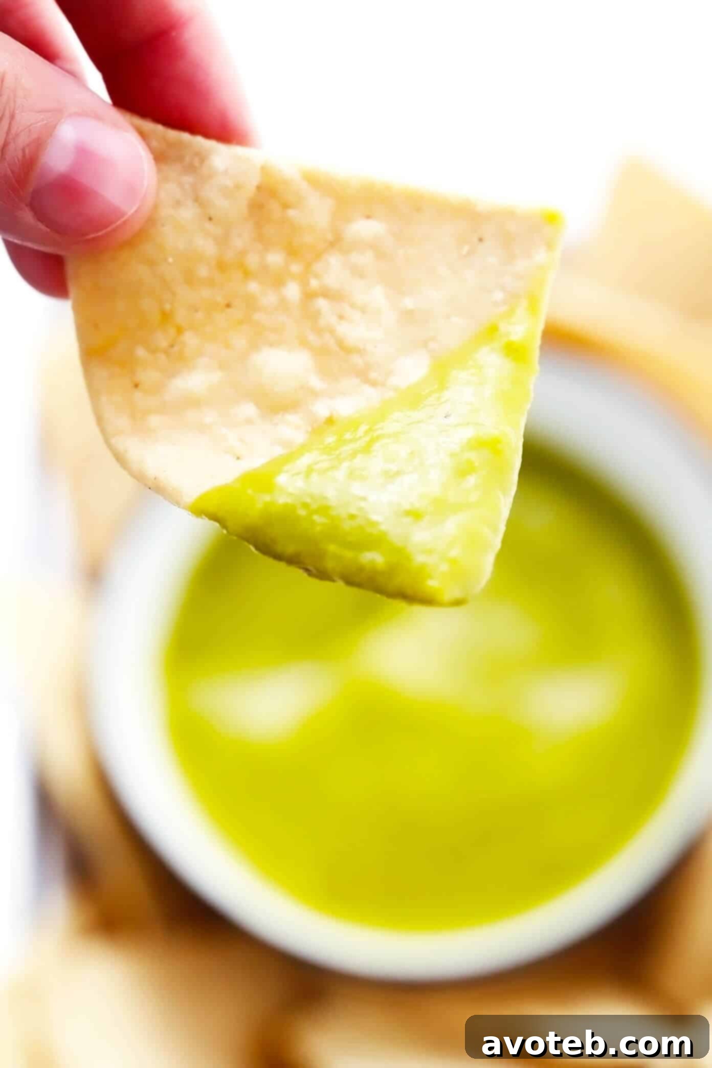 This 5-ingredient creamy jalapeño salsa recipe is easy to make in 30 minutes and irresistibly garlicky and flavorful. Perfect for dipping with chips or drizzling on whatever other Mexican-inspired dishes you love best. It is naturally gluten-free and vegan, and options are included to make this salsa as mild or spicy as you prefer. | gimmesomeoven.com Scooping a tortilla chip into a bowl of creamy jalapeño salsa