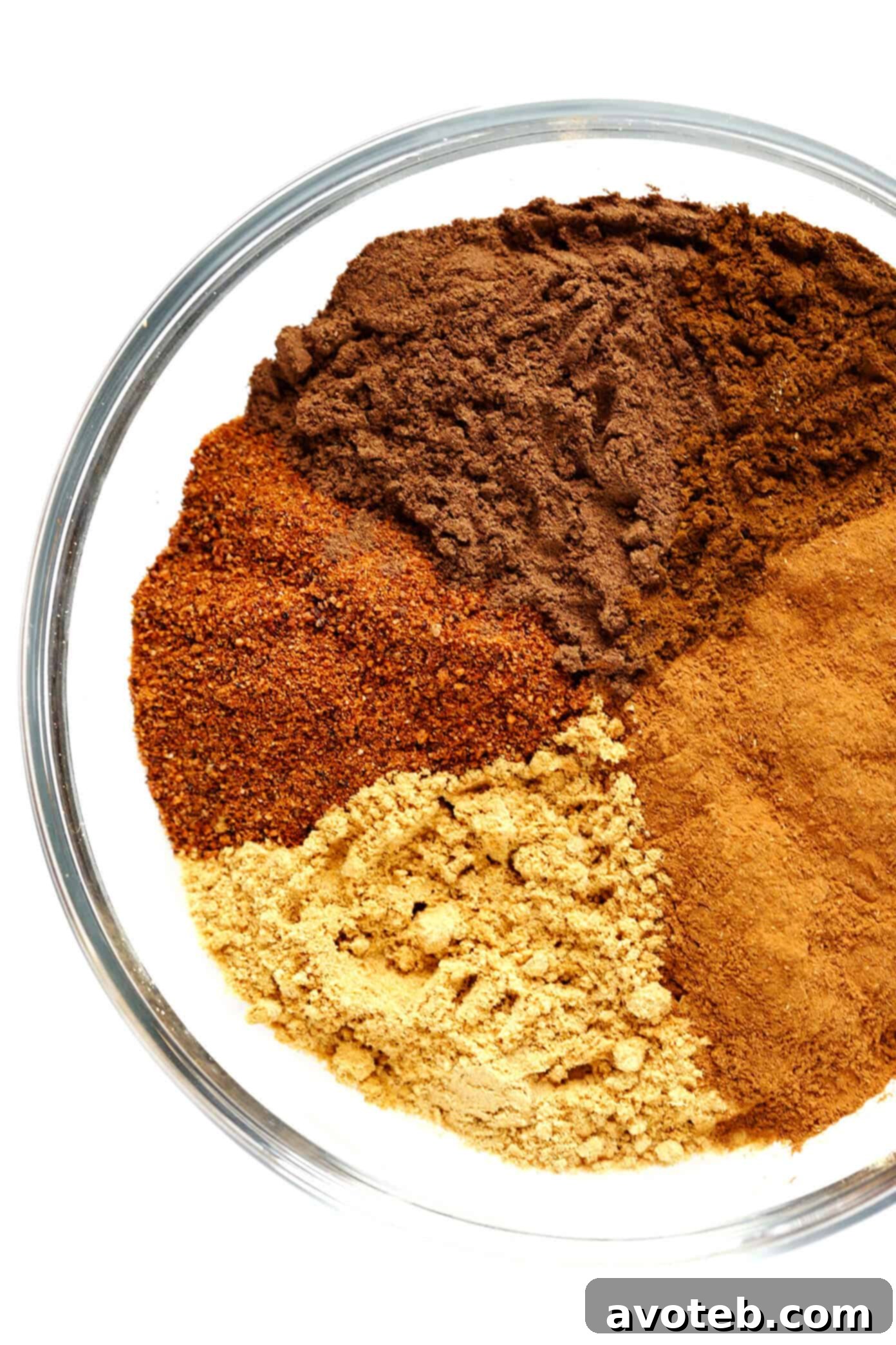 The five essential ingredients for homemade pumpkin pie spice: ground cinnamon, ground ginger, ground nutmeg, ground allspice, and ground cloves, laid out on a surface.