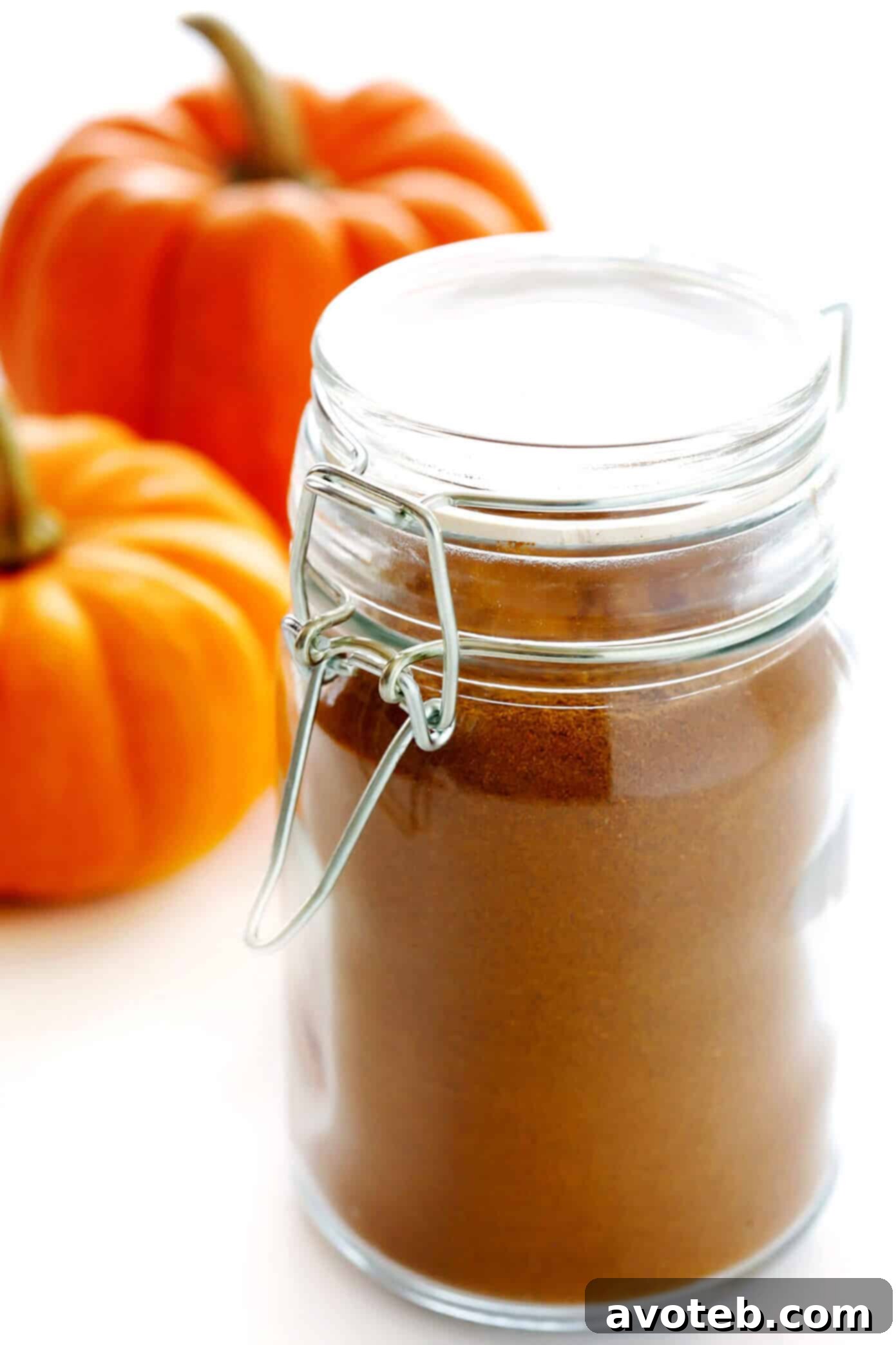 Hands mixing ground spices in a bowl to make homemade pumpkin pie spice, illustrating the simplicity of the process.