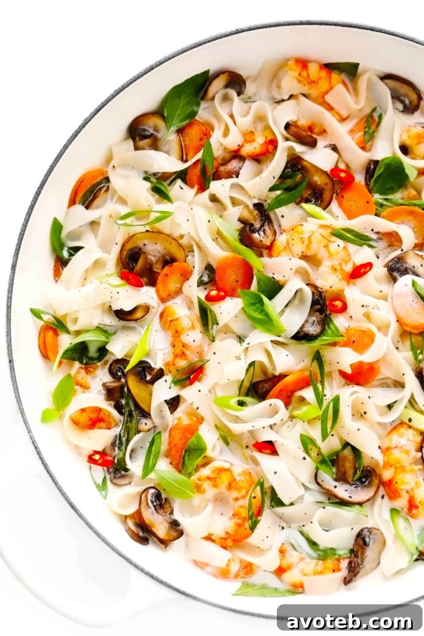 A vibrant and aromatic scene: lemongrass coconut noodles, tender shrimp, sautéed mushrooms, and fresh Thai basil leaves mingling in a large pan. This Thai-inspired stir-fry is infused with zesty ginger coconut sauce, promising bright and delicious flavors for an easy dinner. Lemongrass Coconut Noodles with Shrimp and Thai Basil Cooking in a Pan