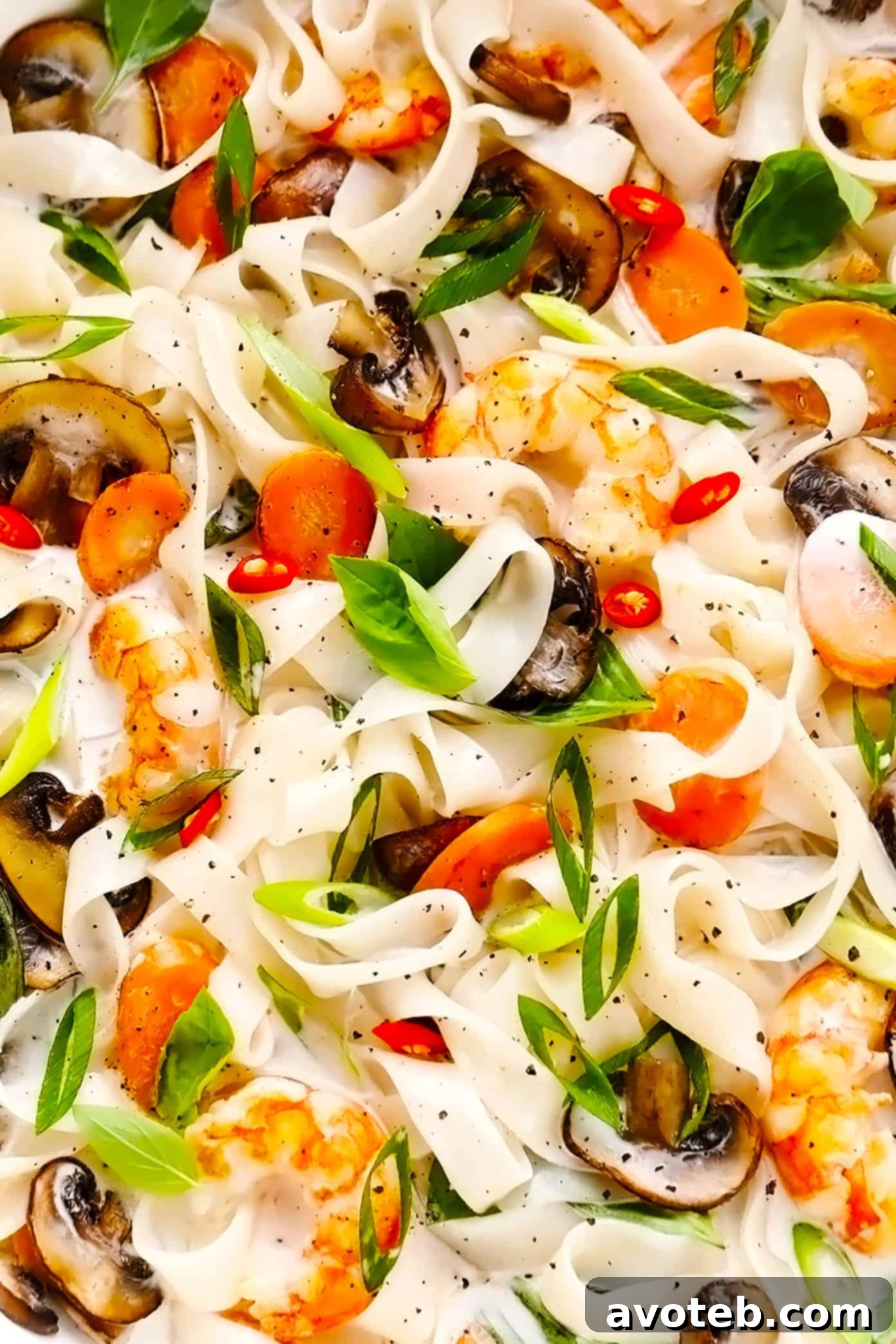 A mouth-watering closeup of lemongrass coconut noodles showcasing tender shrimp, fresh Thai basil, vibrant green onions, and a zesty lime wedge. This Thai-inspired stir-fry is a feast for the senses, rich with bright and citrusy flavors from a savory ginger coconut sauce. Closeup of Lemongrass Coconut Noodles with Shrimp, Thai Basil, and Lime