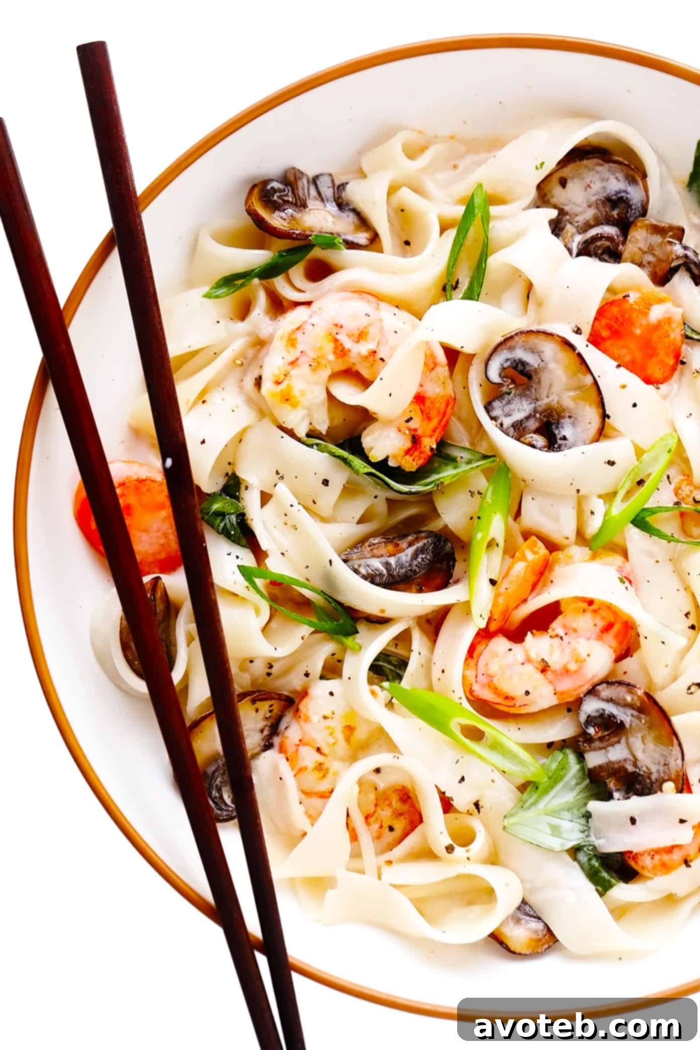 A beautifully arranged bowl of lemongrass coconut rice noodles, featuring plump shrimp, vibrant green onions, and fresh cilantro, ready to be enjoyed with chopsticks. This Thai-inspired dish is a celebration of bright, citrusy, and savory flavors, perfect for a satisfying meal. Bowl of Lemongrass Coconut Rice Noodles with Shrimp and Chopsticks
