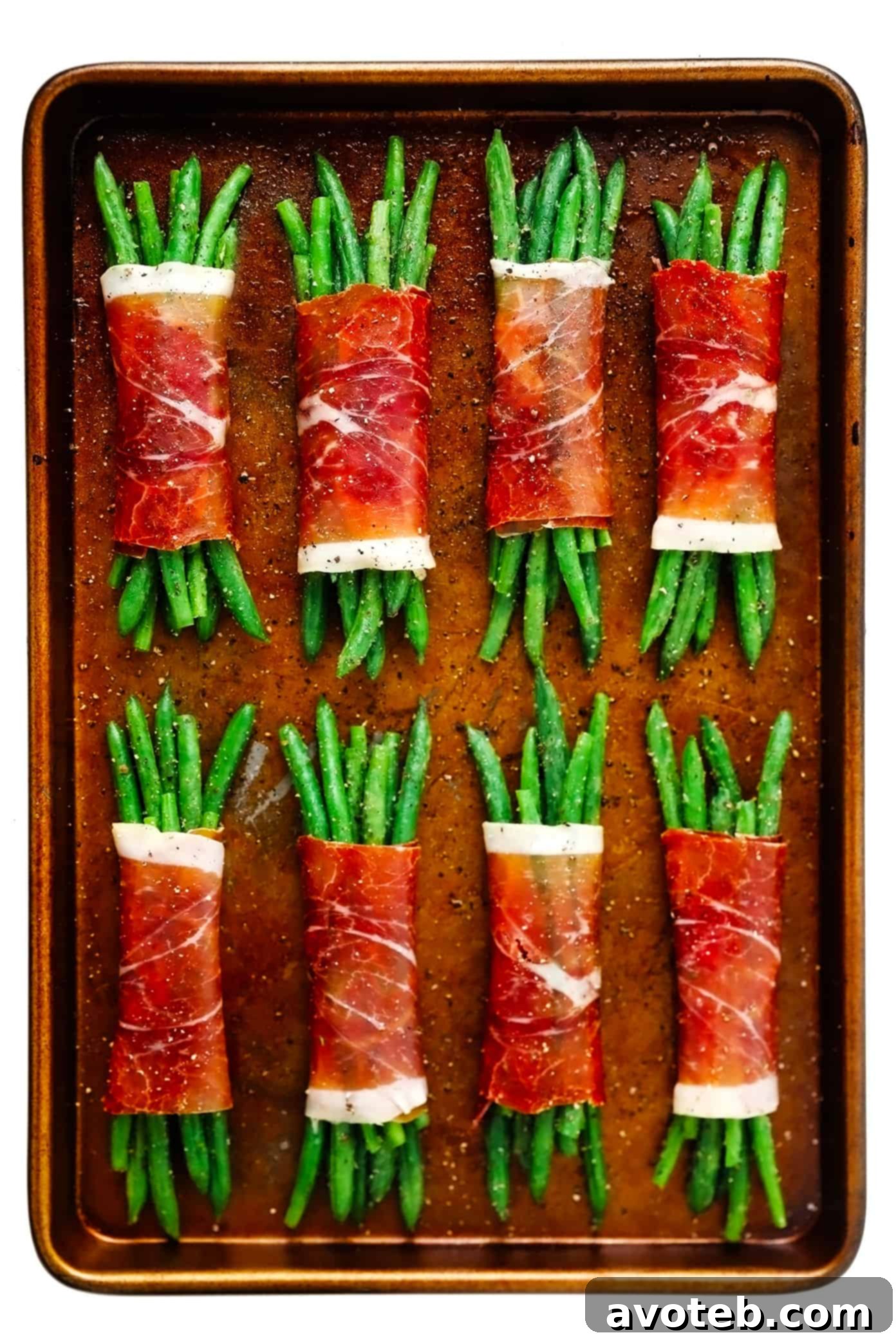 Unbaked Prosciutto-Wrapped Green Bean Bundles arranged neatly on a baking sheet, ready for the oven.