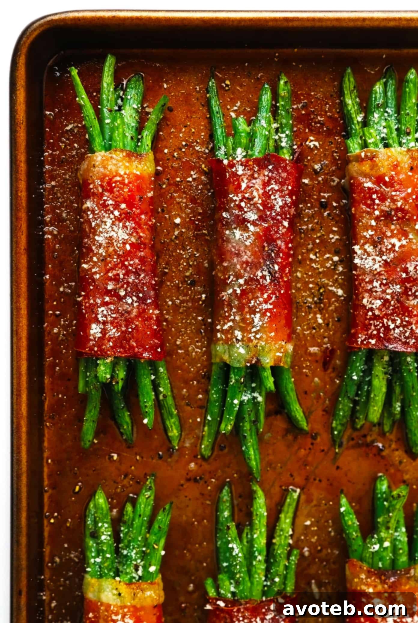 Platter of perfectly roasted Prosciutto-Wrapped Green Bean Bundles with a sprinkle of Parmesan, ready for serving.