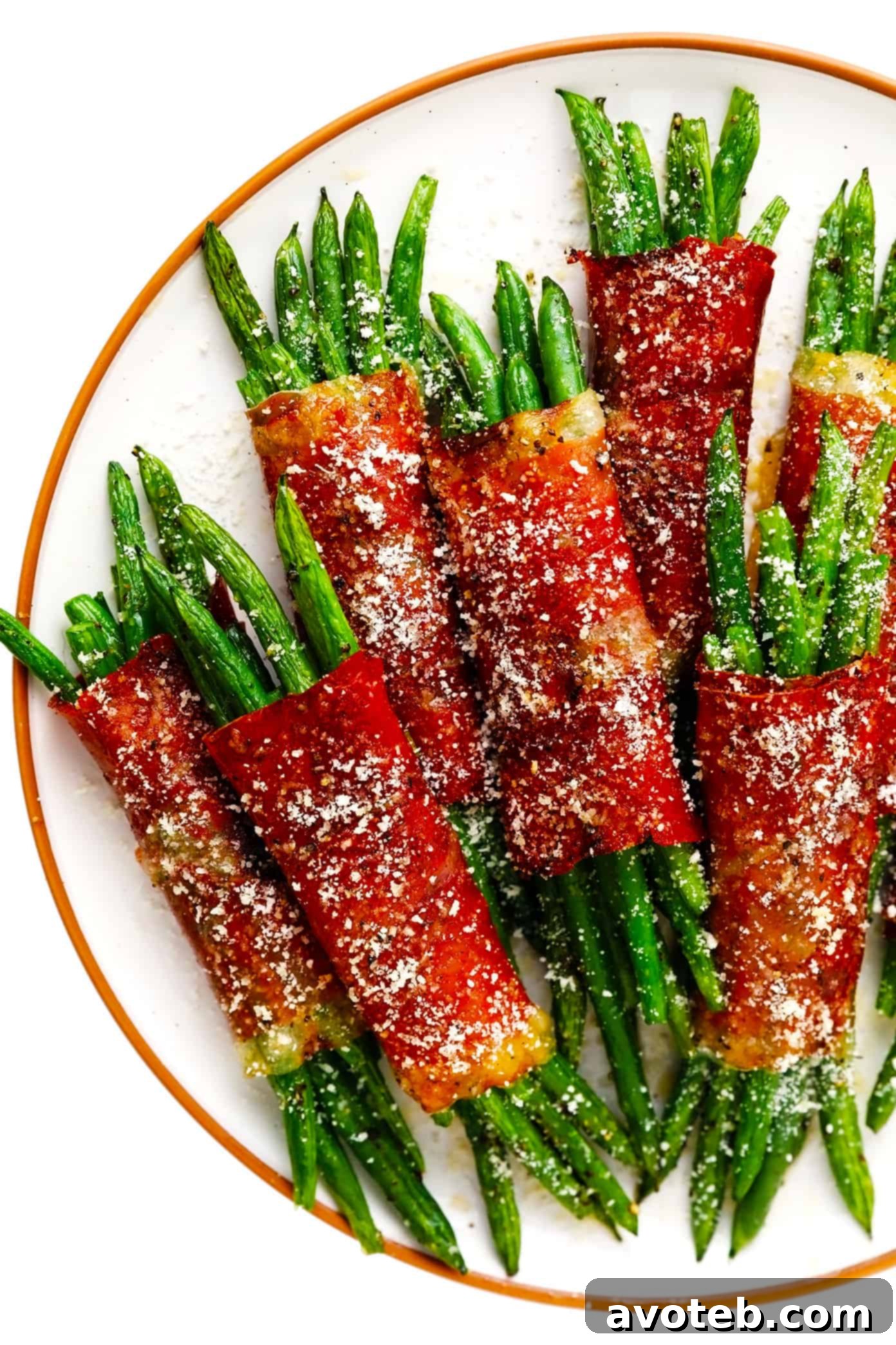 Beautifully presented roasted Green Bean Bundles with Prosciutto on a white serving plate, garnished with fresh Parmesan.