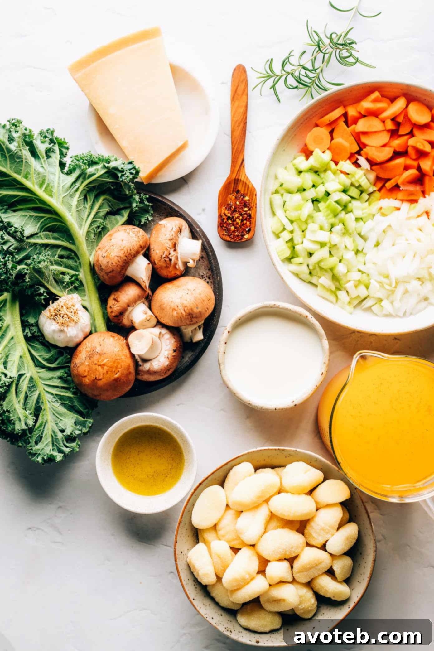 Fresh ingredients for Gnocchi, Mushroom, and Kale Soup, including gnocchi, sliced mushrooms, kale, carrots, celery, and garlic, laid out on a rustic surface.