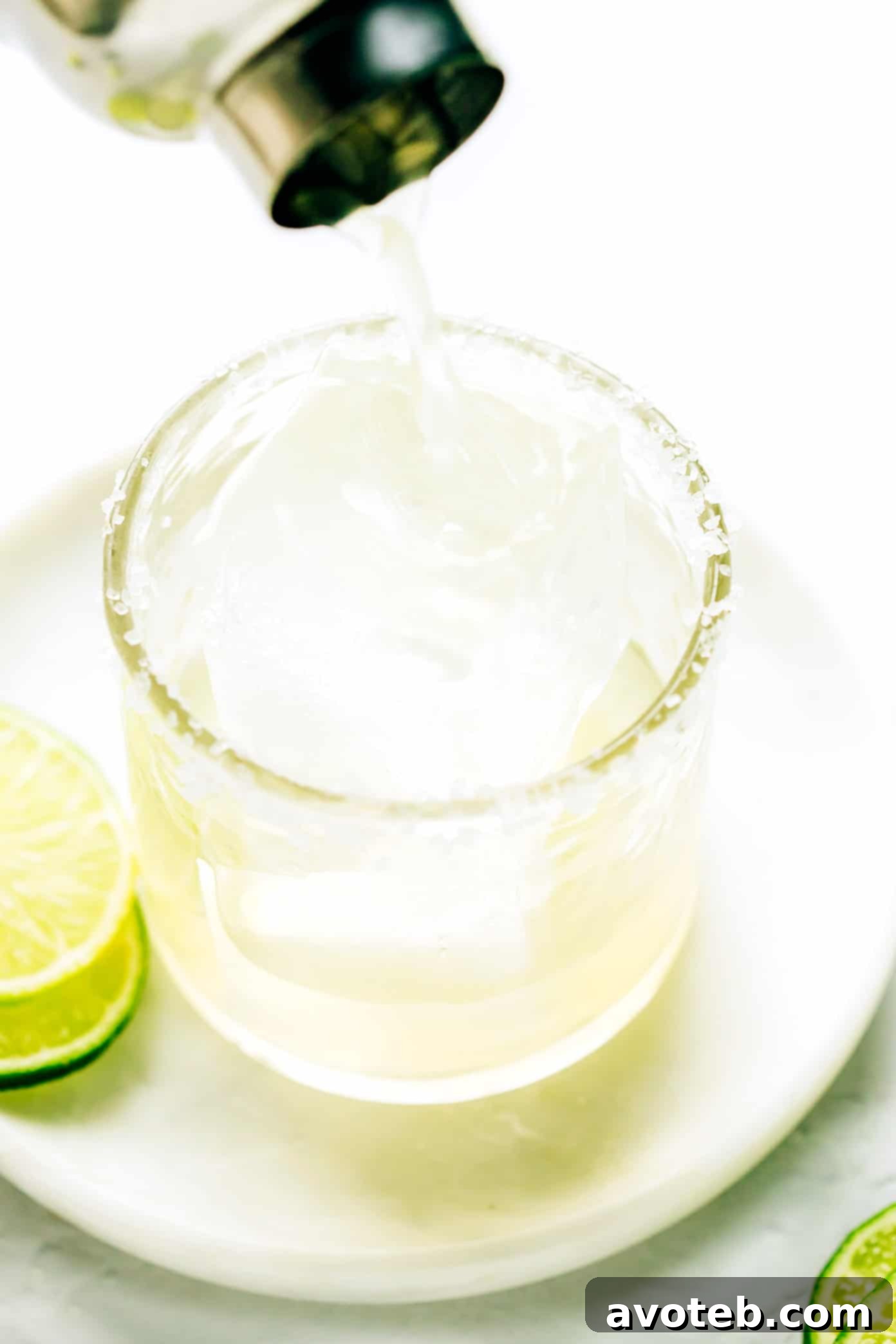 Pouring a bourbon margarita into a salt-rimmed glass