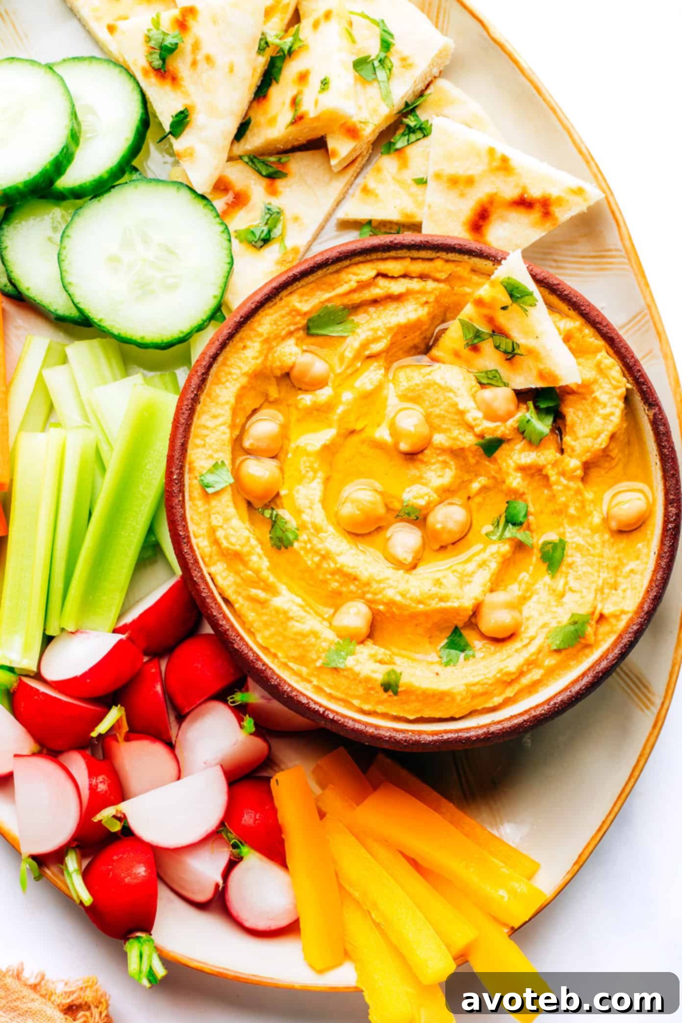 Vibrant Thai Red Curry Hummus in a bowl, garnished with fresh cilantro and a drizzle of olive oil, ready to be served.