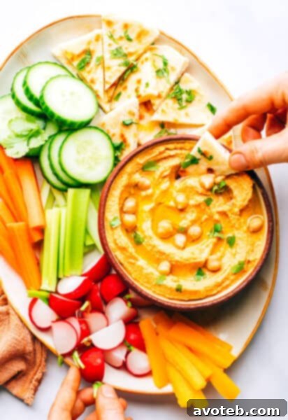 Red Curry Hummus served on a platter with fresh vegetables and naan.