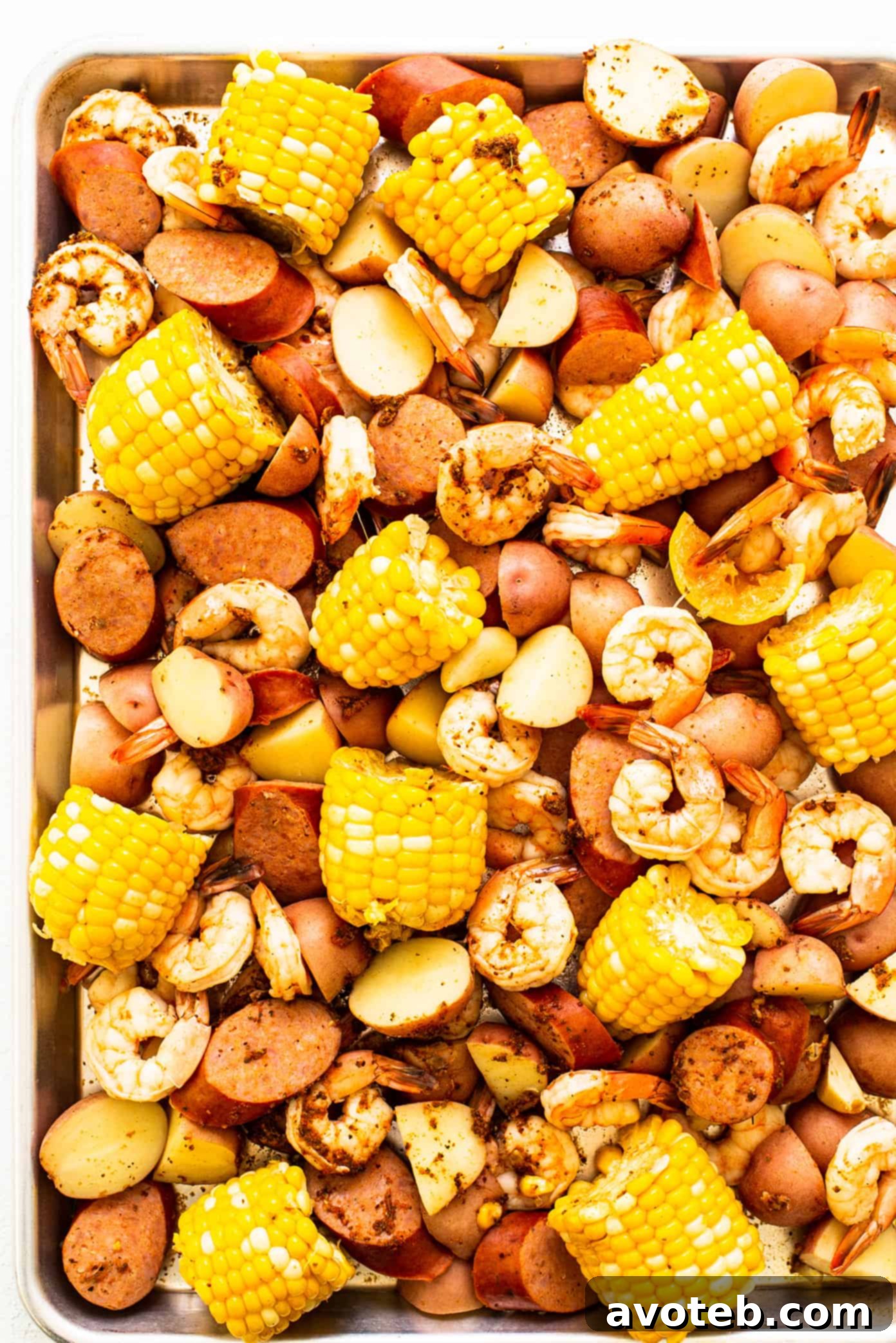 Cooked shrimp boil served on a large sheet pan, garnished with fresh herbs