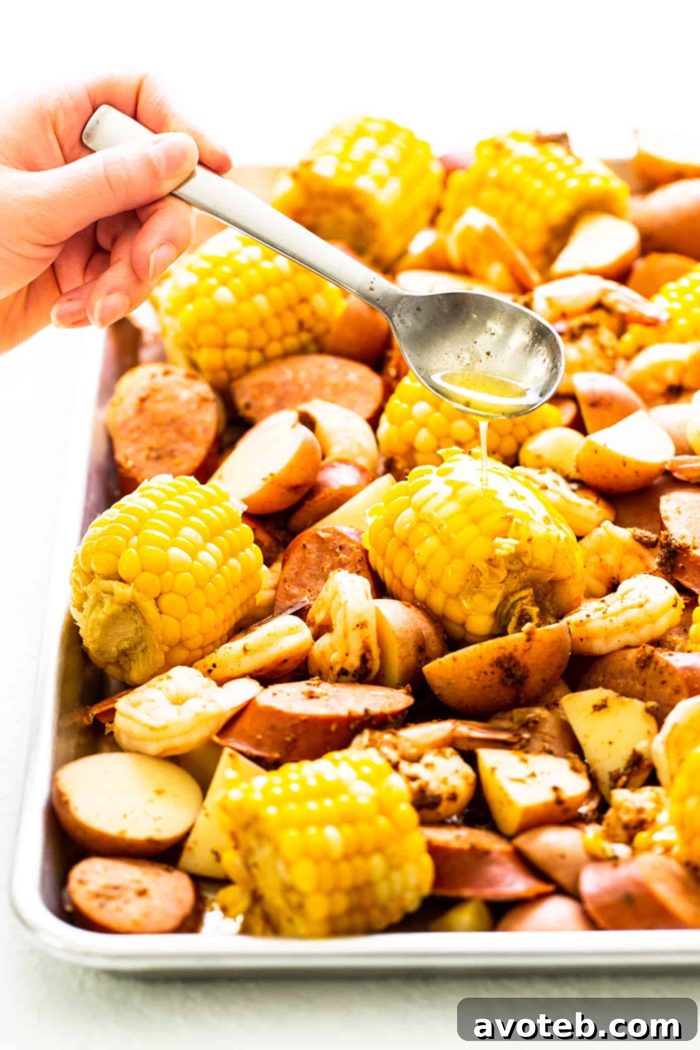 Drizzling lemon garlic brown butter sauce over a sheet pan shrimp boil