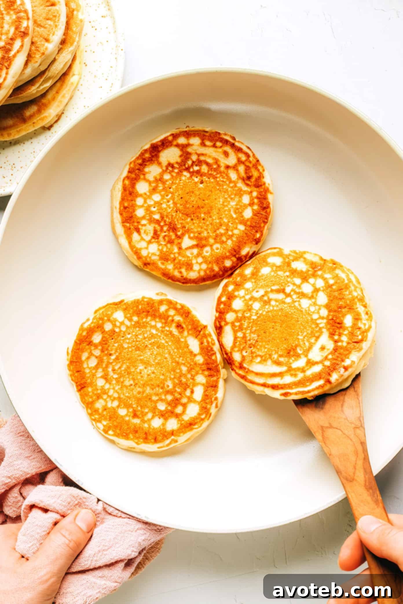 Fluffy Kefir Pancakes from Barclay 6 An inviting overhead shot of a breakfast table laden with a generous stack of fluffy kefir pancakes, surrounded by an assortment of delicious toppings like fresh berries, maple syrup, and whipped cream, ready for a family meal.