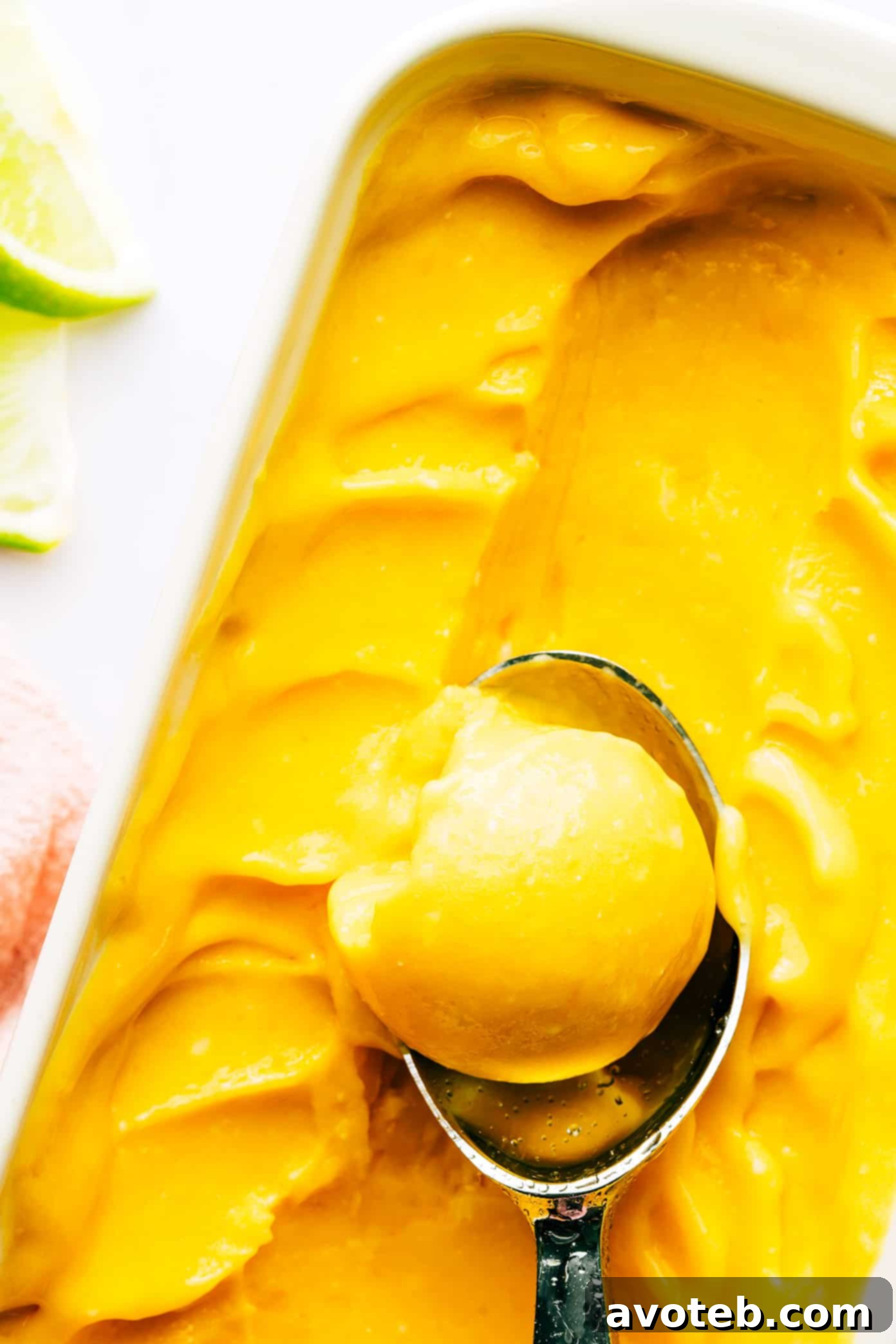 Mango Lime Sorbet in pan with ice cream scoop, ready to serve.