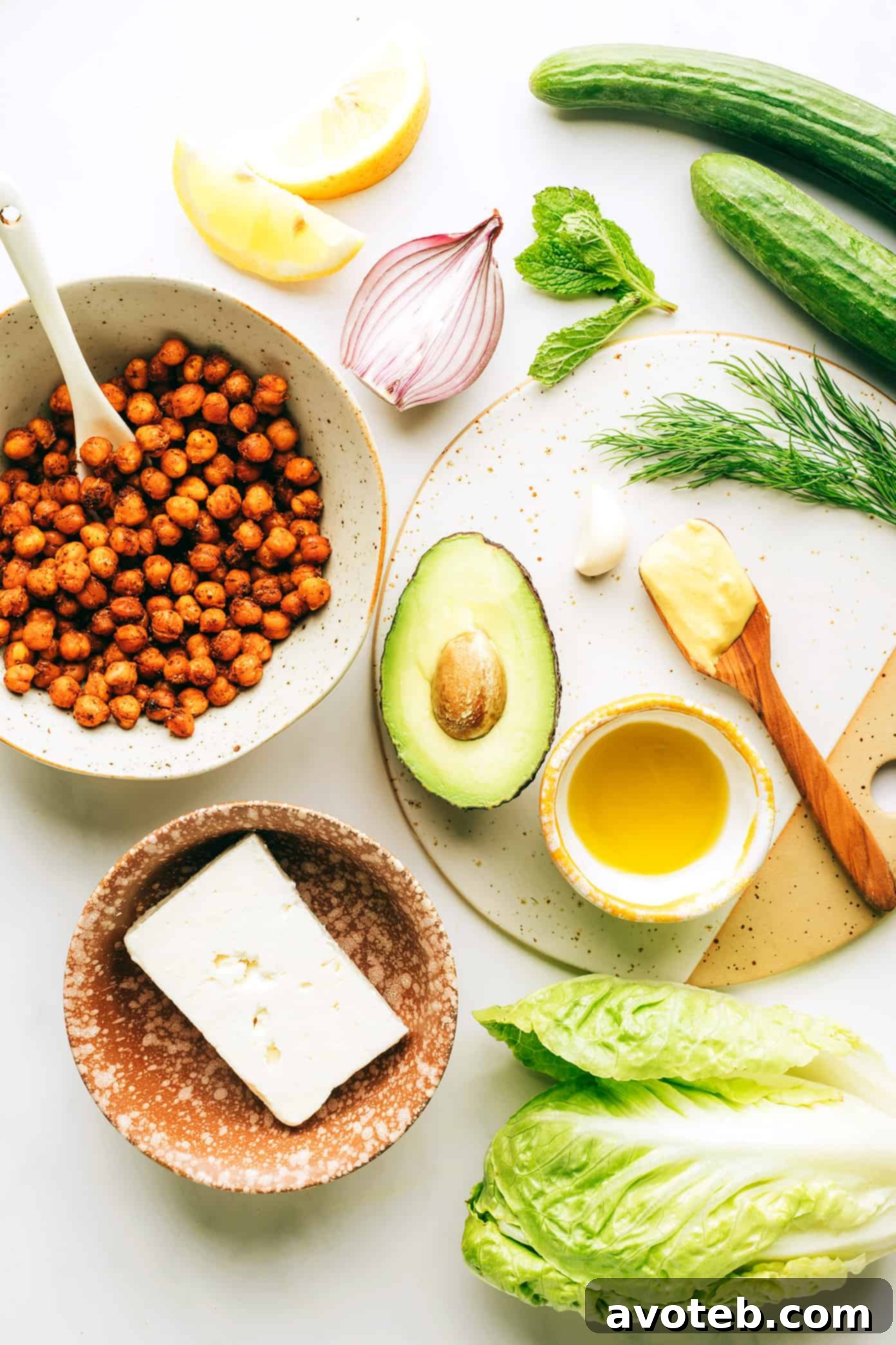 Close-up of the fresh ingredients for the salad, including vibrant Romaine lettuce, cool cucumber slices, creamy avocado chunks, thinly sliced red onion, and fragrant fresh herbs, arranged on a chopping board, ready for preparation.