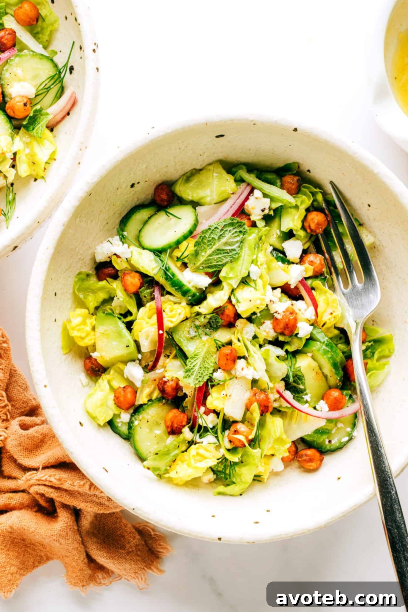 A close-up of a generous serving of the roasted chickpea, avocado, and cucumber salad in a rustic ceramic bowl, presented beautifully and ready to be enjoyed.