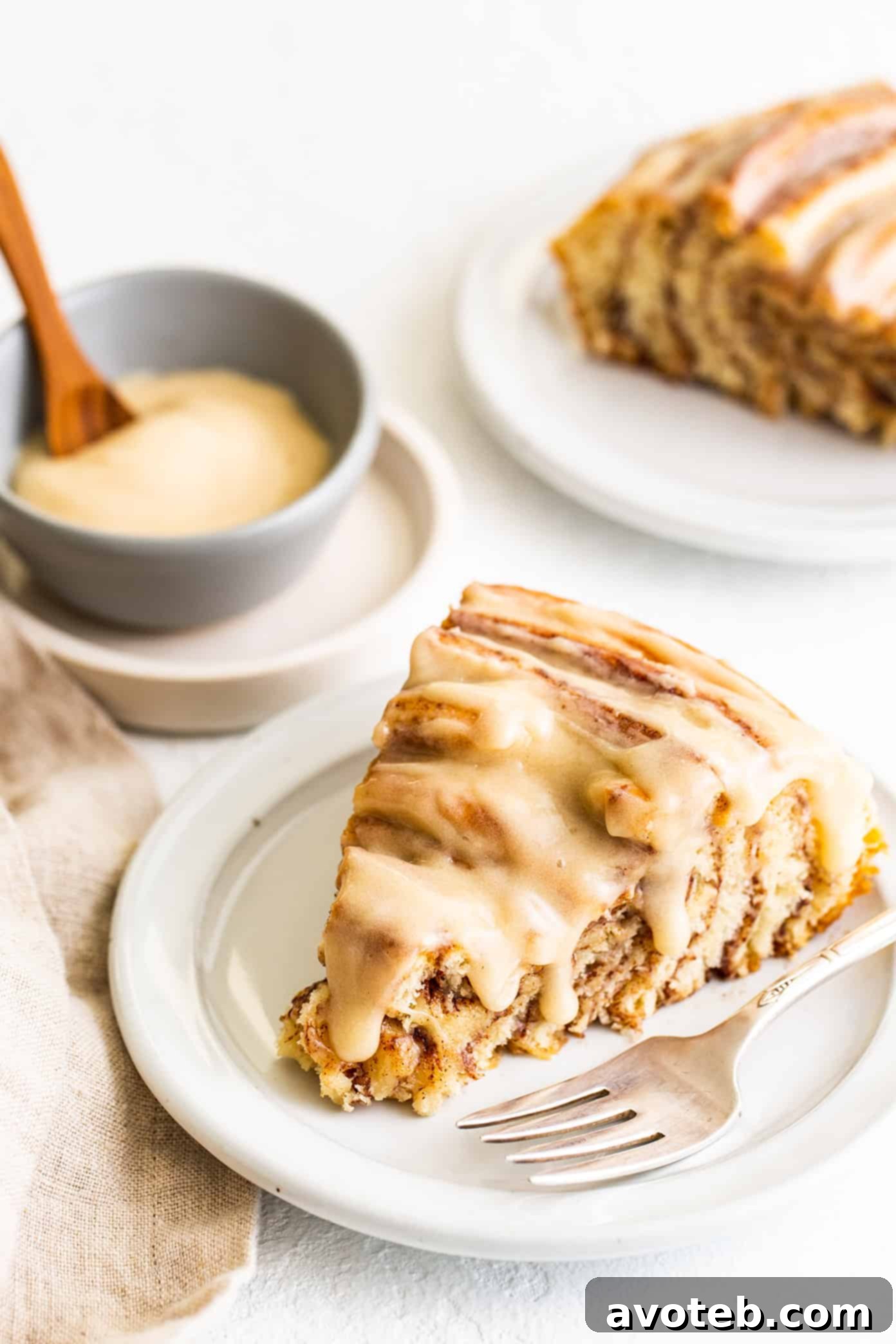 Slices of giant cinnamon roll, generously frosted with cream cheese icing and drizzled with extra glaze, ready to be served