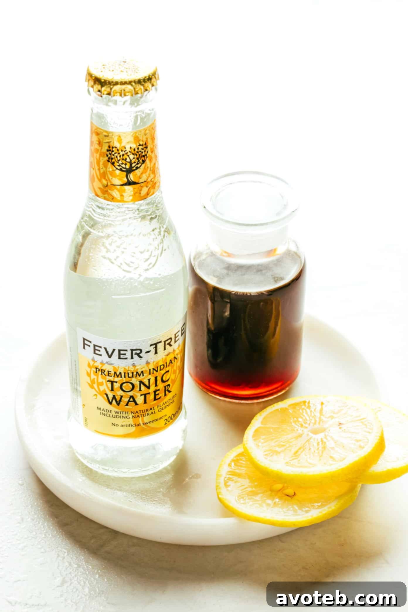 Ingredients for Cold Brew Tonic laid out on a plate: a bottle of cold brew concentrate, tonic water, a lemon, and ice cubes.