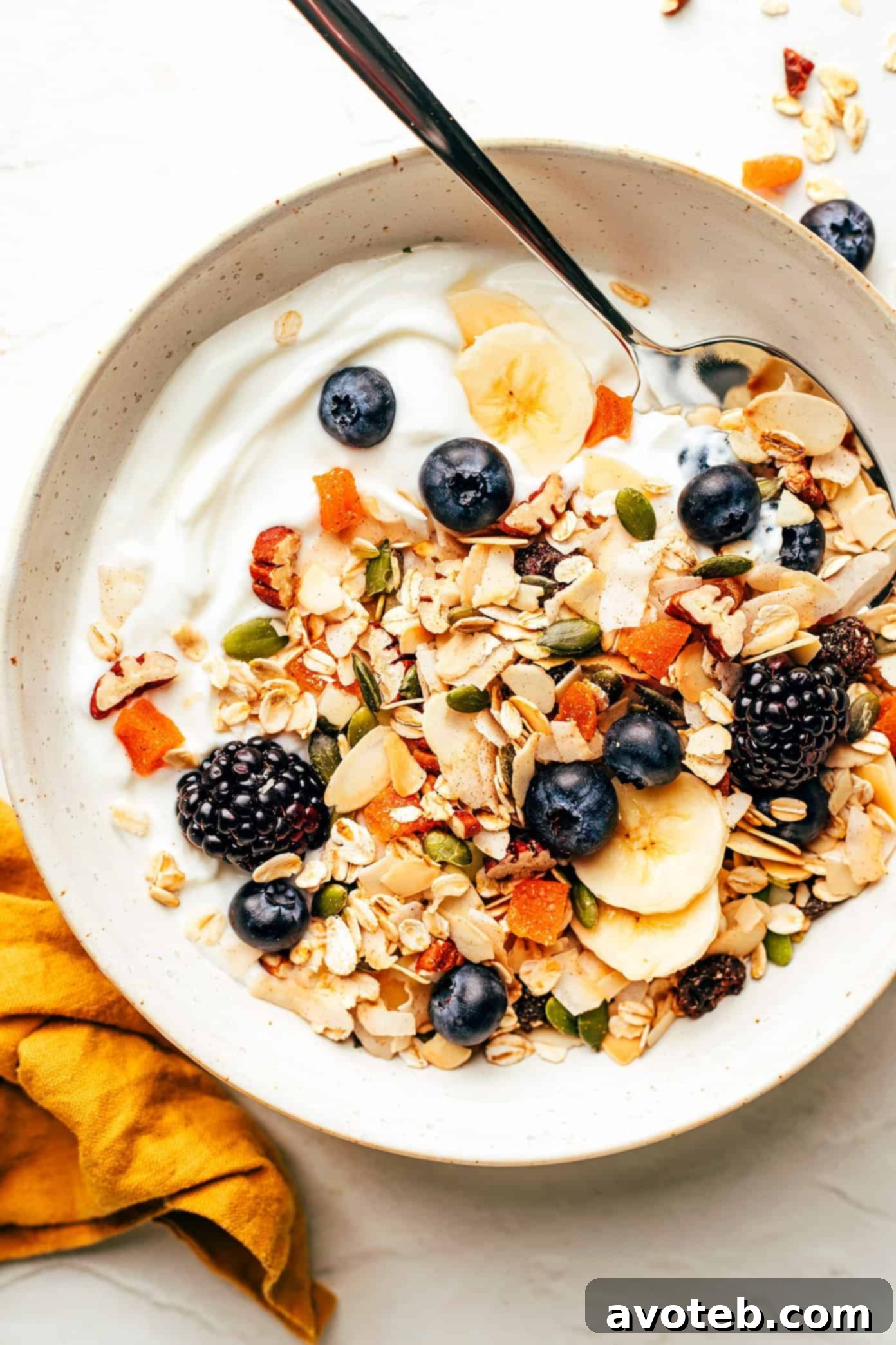 This delicious homemade muesli recipe is easy to make and customize with your favorite blend of oats, nuts, seeds, dried fruit, coconut (optional) and spices. Serve with hot or cold milk, prep "overnight oats"-style, layer as a parfait with Greek yogurt, or however you love best. Always such a great healthy and easy breakfast! | gimmesomeoven.com A vibrant breakfast parfait featuring layers of homemade muesli, creamy Greek yogurt, fresh blueberries, and sliced bananas, topped with a few whole berries for garnish.