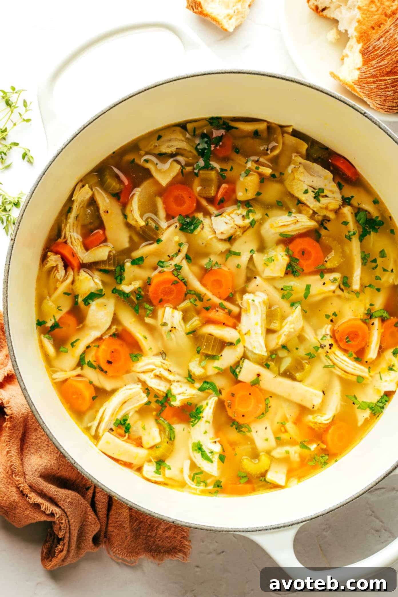 A large pot of homestyle chicken noodle soup garnished with fresh parsley, ready to be served.