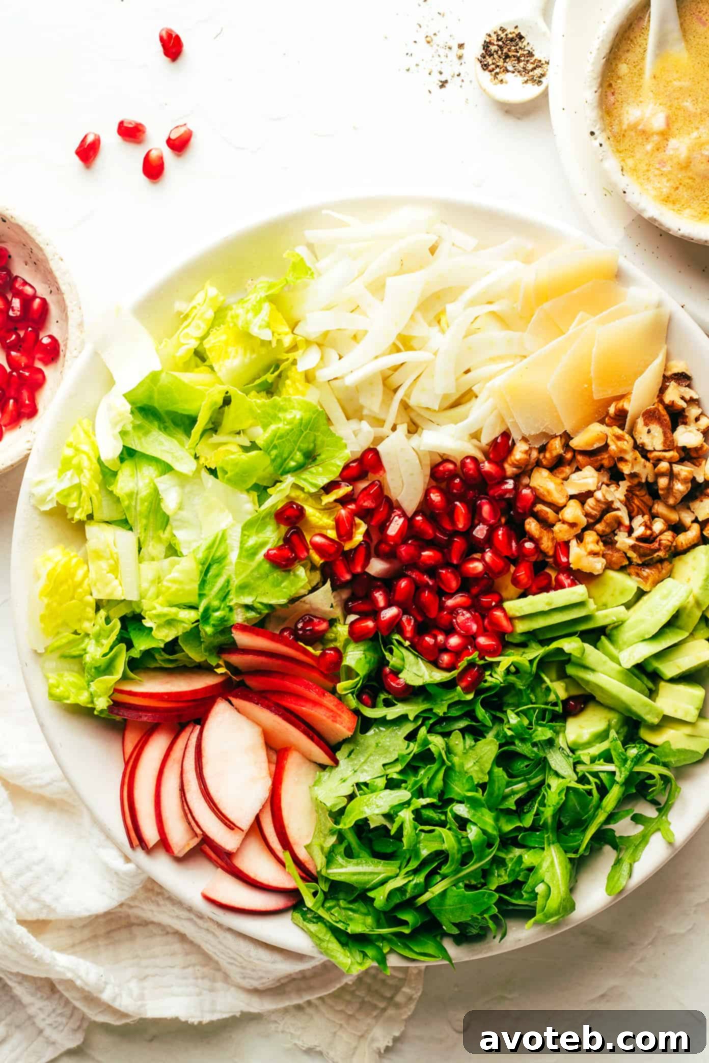 A colorful array of ingredients for your holiday salad: fresh pomegranate, crisp apple, peppery arugula, creamy avocado, toasted walnuts, sharp Parmesan, fragrant fennel, and a homemade shallot vinaigrette. Ingredients for a Perfect Holiday Green Salad: Pomegranate, Apple, Arugula, Avocado, Walnuts, Parmesan, Fennel, Lettuce, and Shallot Vinaigrette