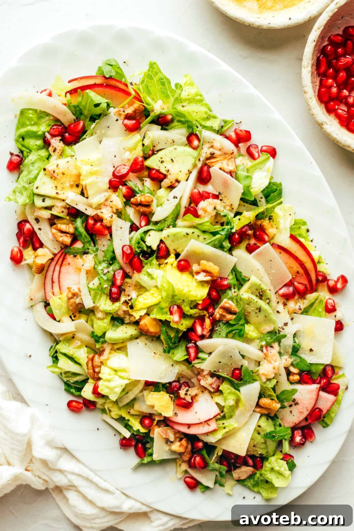 A stunning Thanksgiving centerpiece: this vibrant green salad artfully arranged with pomegranate, apple, avocado, Parmesan, fennel, and toasted walnuts, ready to impress your guests. Beautifully presented Thanksgiving Green Salad platter with pomegranate, apple, avocado, Parmesan, fennel, and walnuts