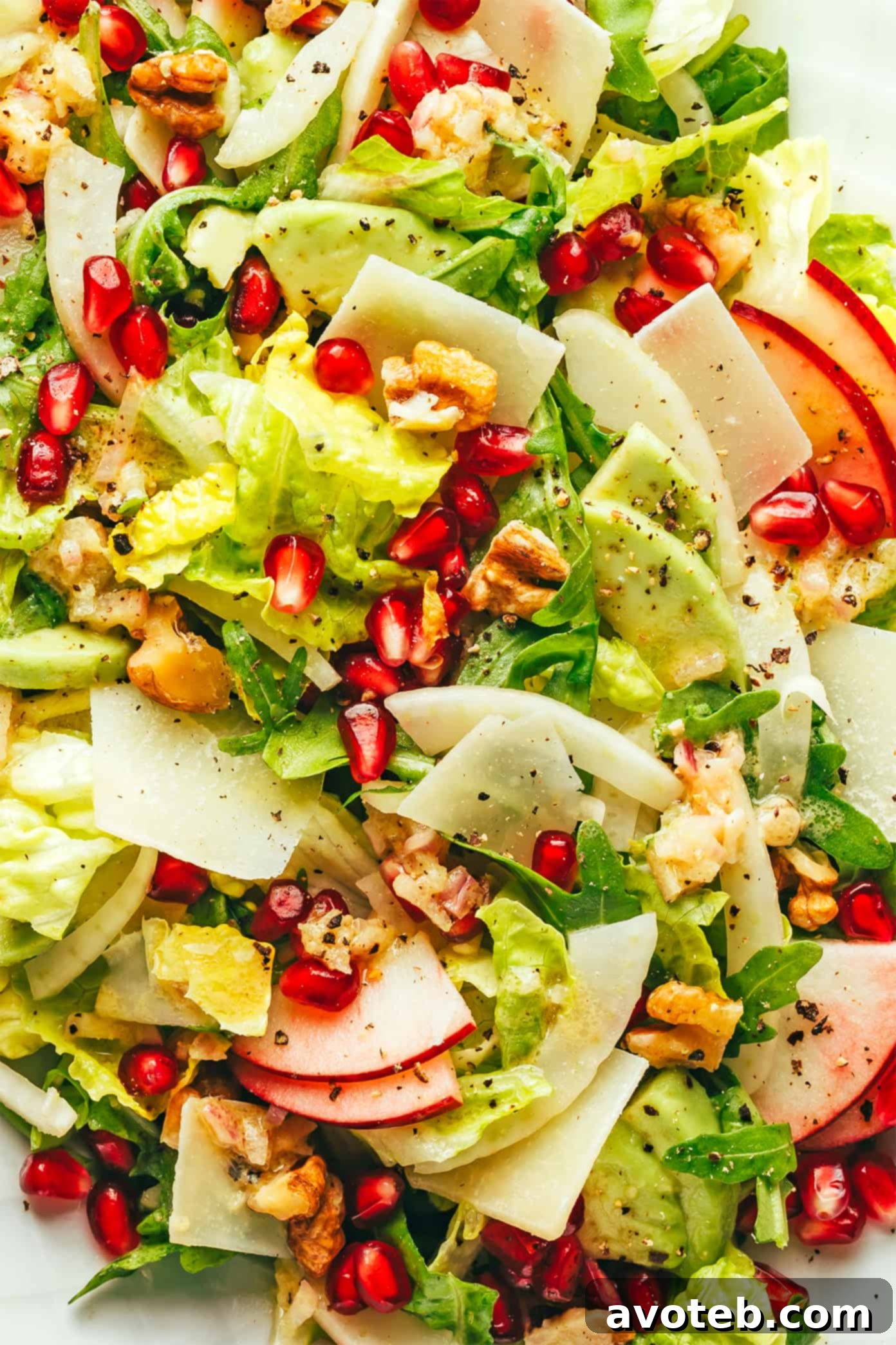 A mouthwatering close-up of the Christmas pomegranate salad, showcasing the delightful textures of crisp apple, juicy pomegranate arils, savory Parmesan, and crunchy walnuts. Close-up of a festive Christmas Pomegranate Salad, highlighting the vibrant colors and fresh ingredients