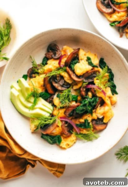 A simple yet elegant spinach mushroom egg scramble with avocado and fresh herbs.