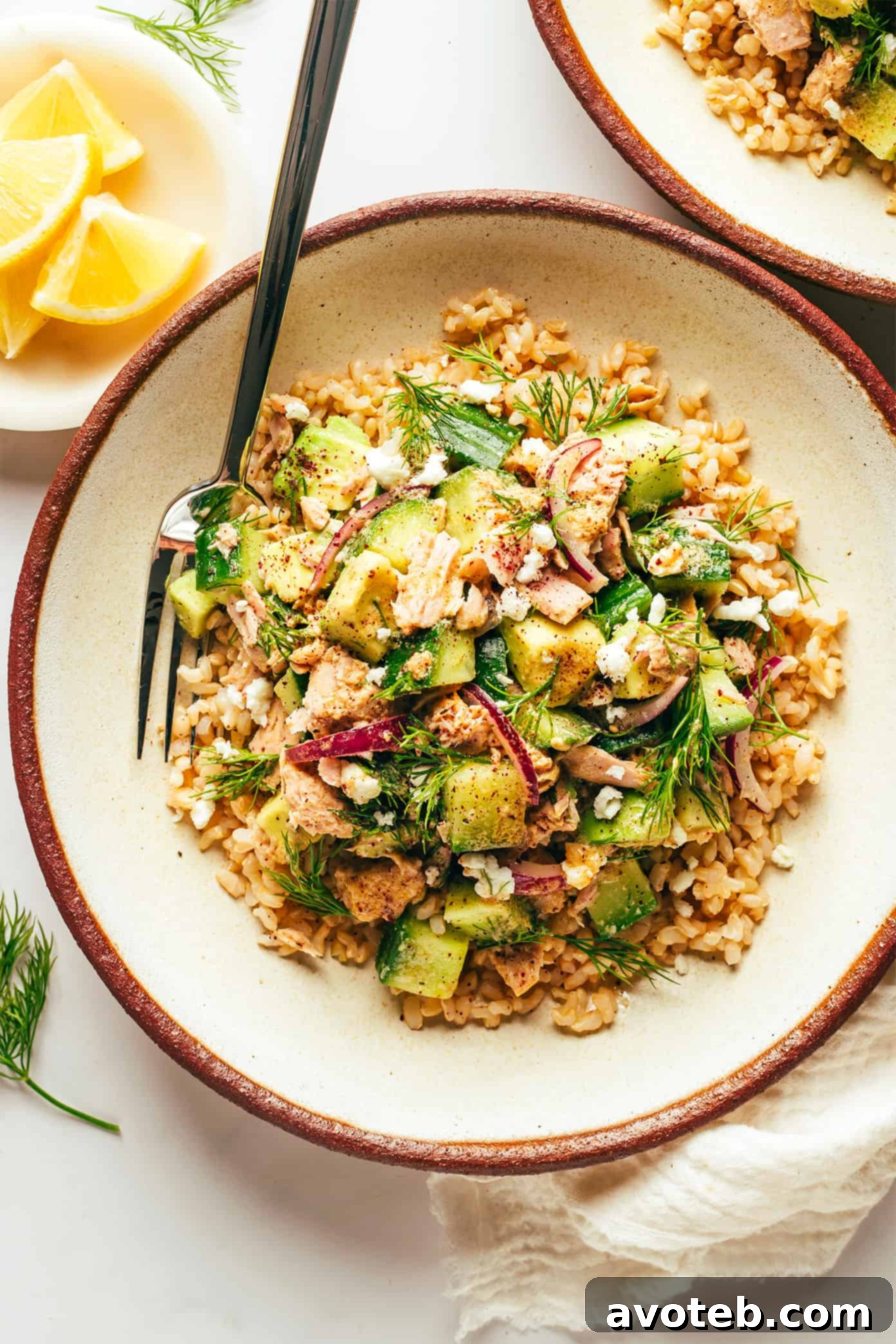 Full spread of Tuna Avocado Brown Rice Bowls, garnished with fresh lemons and herbs, ready to be served.