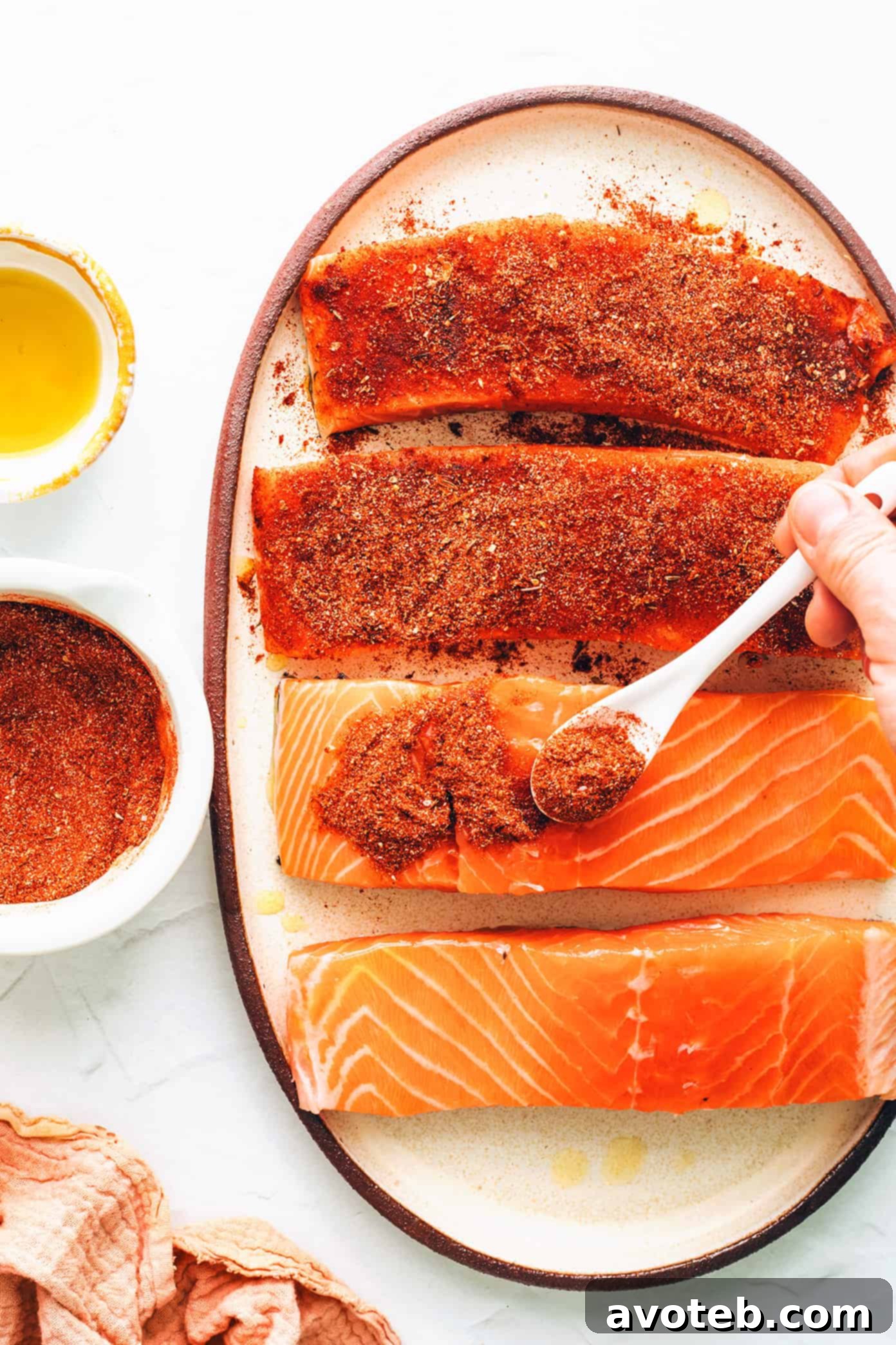Generously seasoning salmon fillets with homemade blackened spice blend