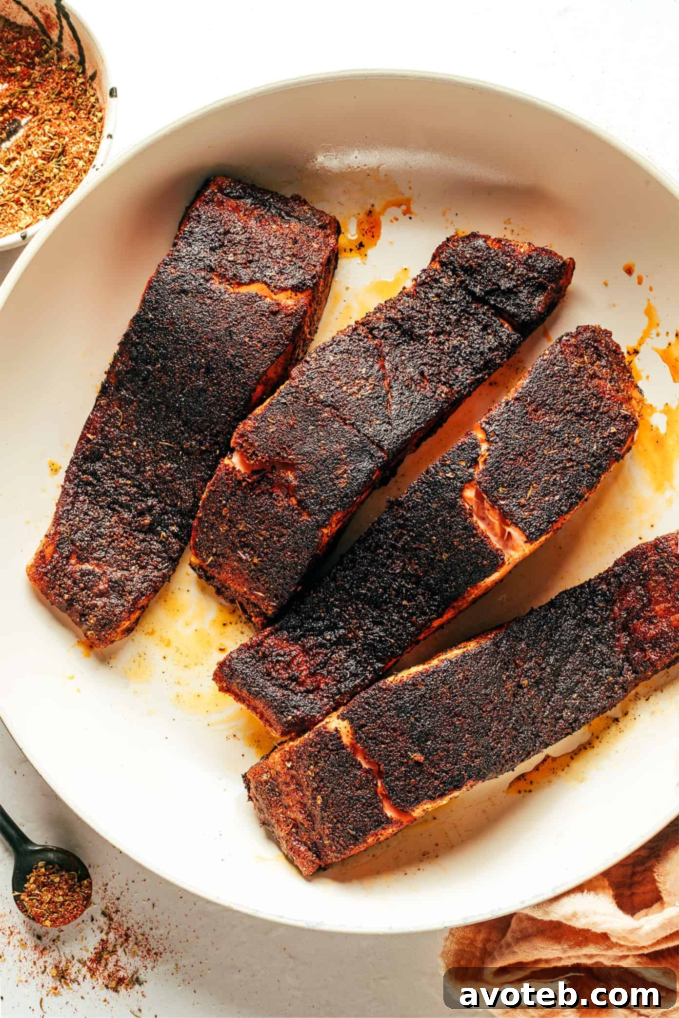 Blackened salmon fillets searing in a hot cast iron pan