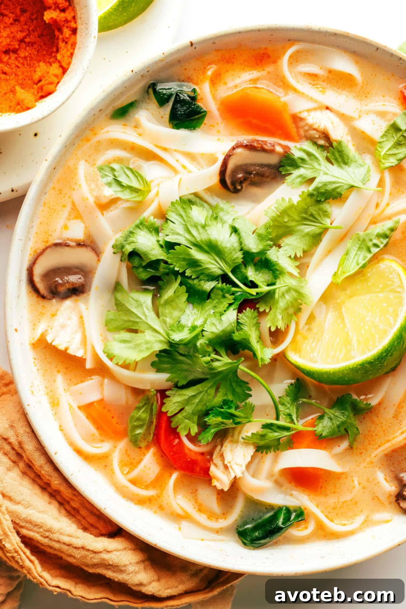 Aromatic Thai Chicken Noodle Bowl 6 Close-up of a steaming bowl of Thai chicken noodle soup with vibrant herbs and noodles.