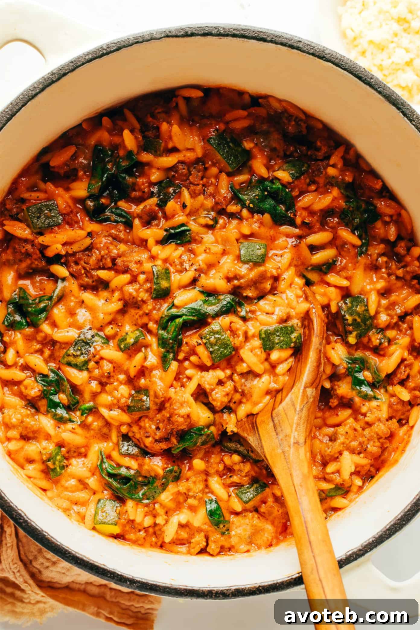 Rustic Italian Sausage Zucchini Orzo 2 Close-up of a steaming pot of Italian Sausage Zucchini Orzo pasta, garnished with fresh basil and Parmesan cheese.