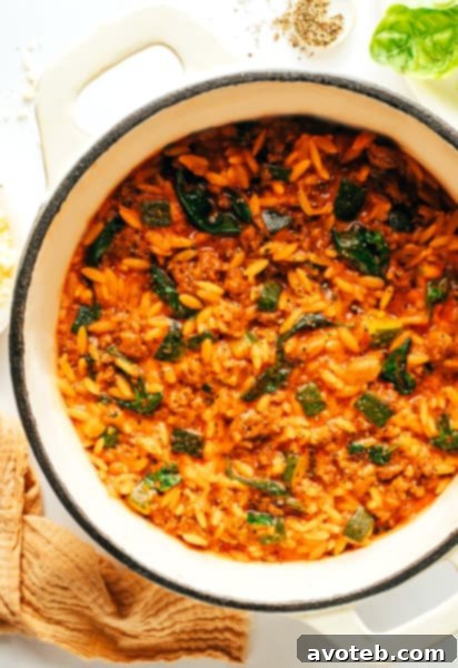 A serving of Italian Sausage Zucchini Orzo with a fork, garnished with fresh basil.