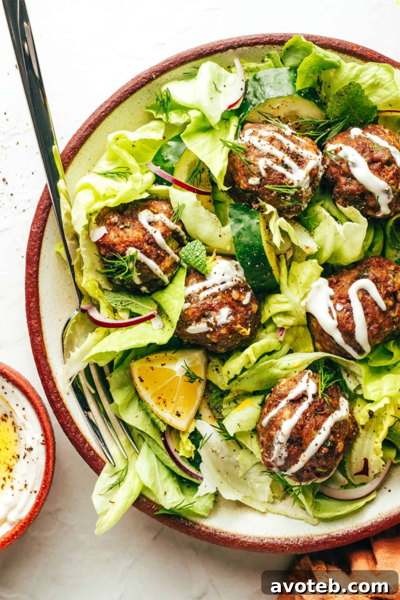 A vibrant Greek salad with homemade Greek Meatballs and a creamy dressing