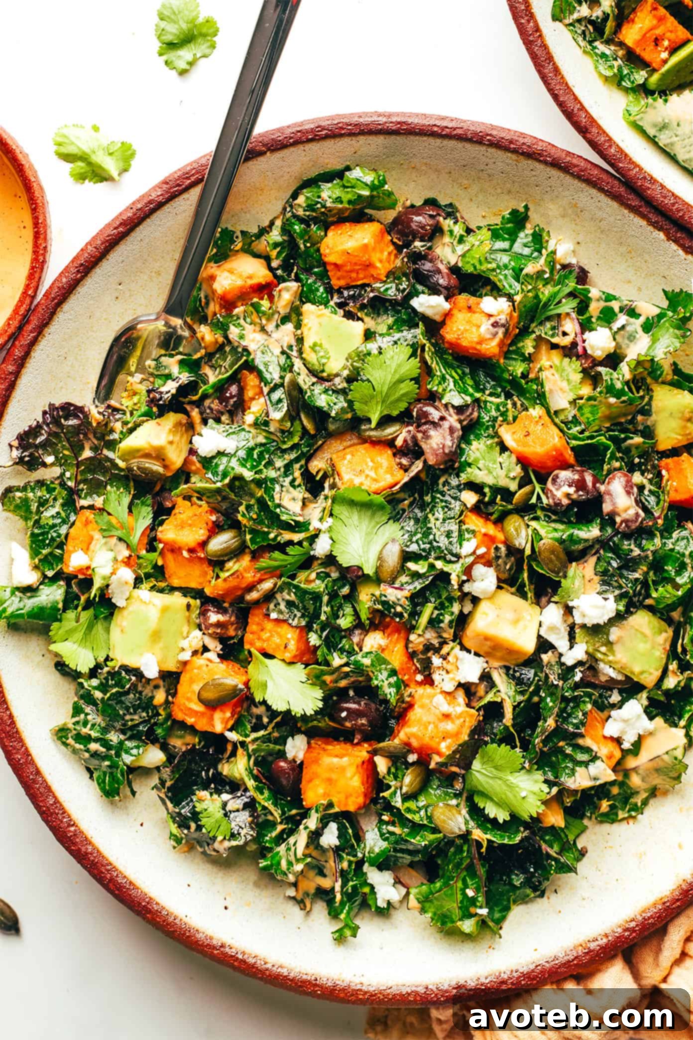 Roasted sweet potato avocado kale salad in a bowl with a fork, ready to be enjoyed as a healthy and flavorful meal.